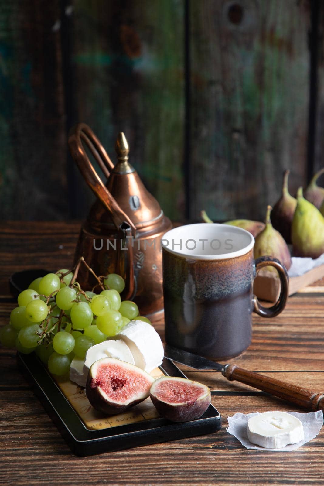 cheese plate with goat cheese, grapes and figs, copper teapot, angle view, healthy food, high-calorie breakfast. High quality photo