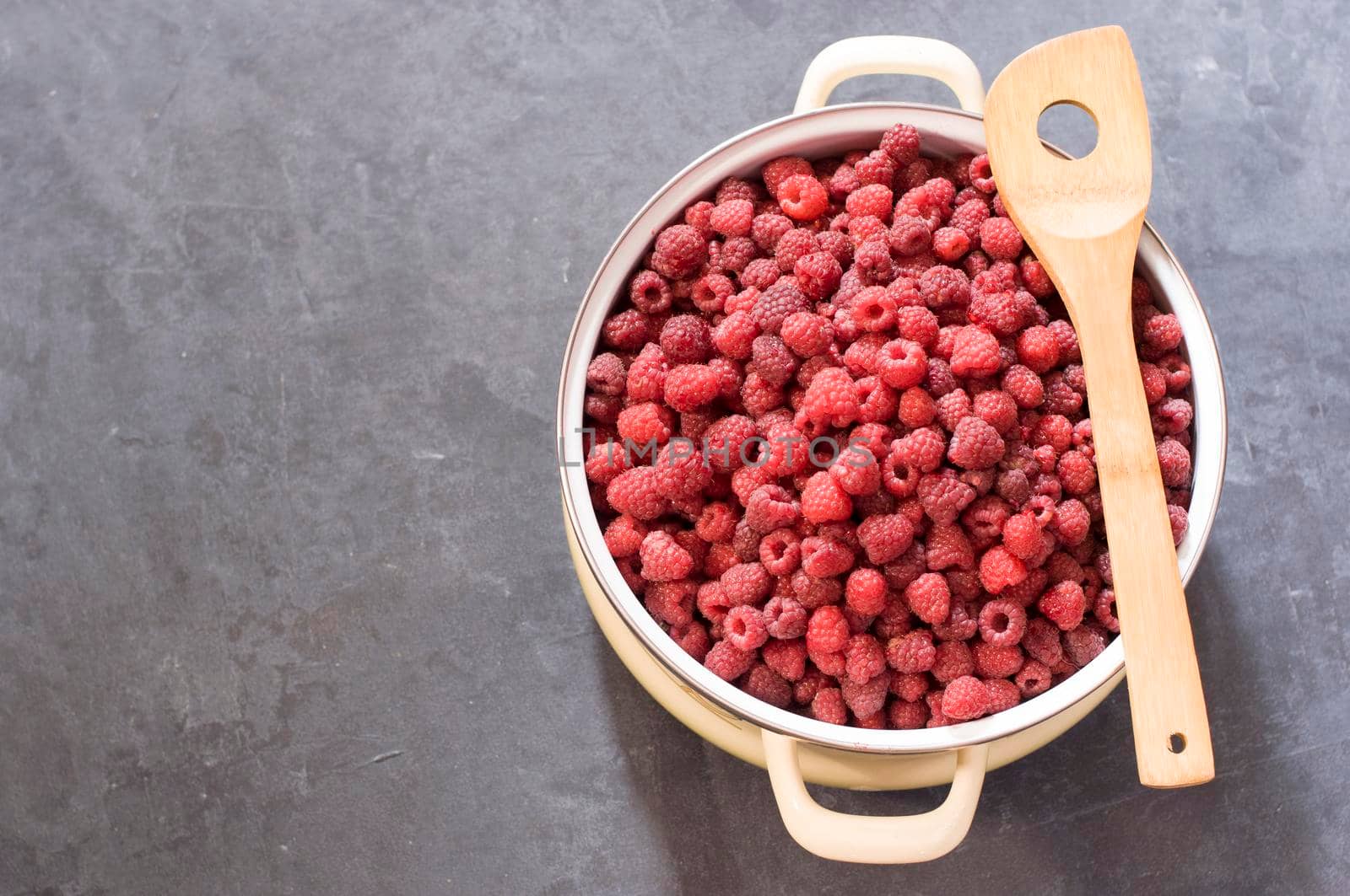 a full pan of ripe raspberries and a spoon for jam, a large harvest of berries by KaterinaDalemans