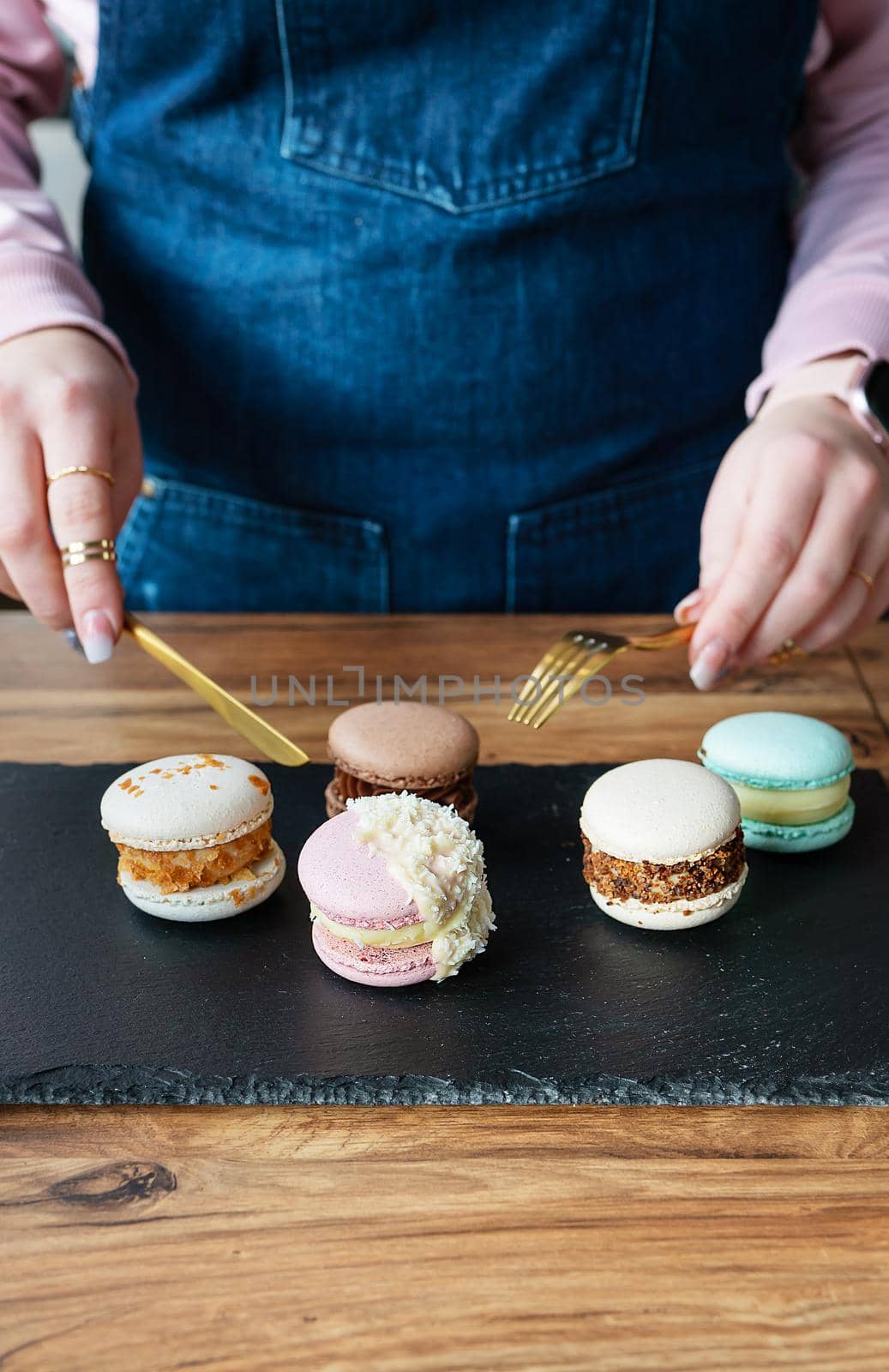 A delicious pasta dessert - a French sweet delicacy lies on a concrete black stand and a girl with a knife and fork cuts sweets