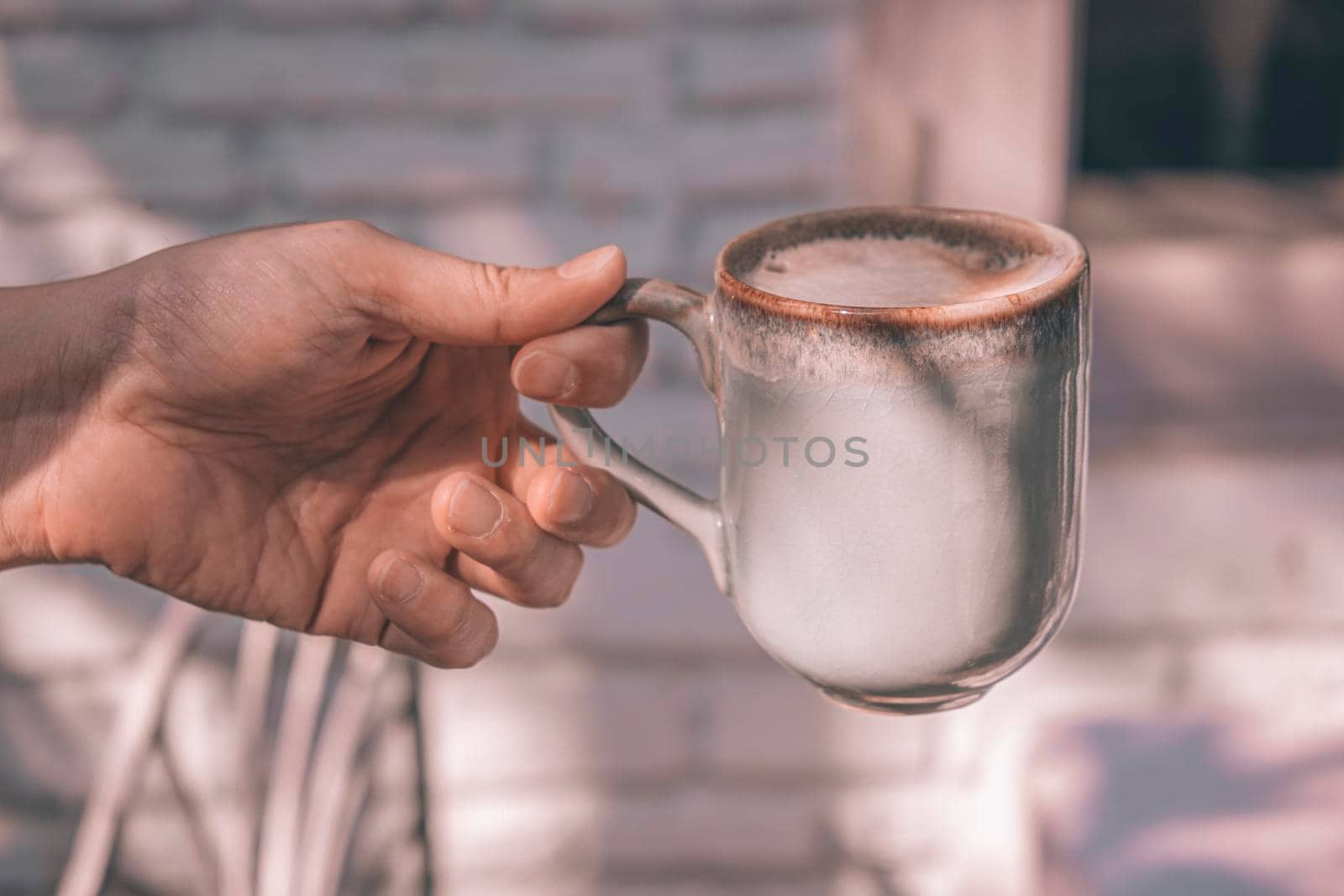 Hands of a man or barista holding cup of hot coffee latte with heart shaped foam art