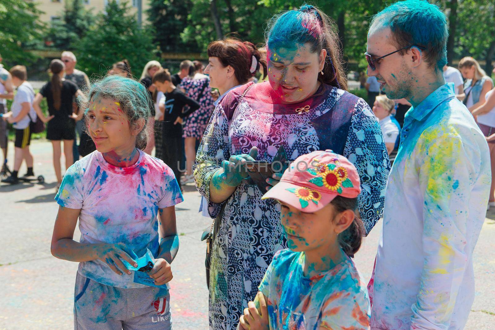 Novokuznetsk, Kemerovo region, Russia - June 12, 2022 :: Happy family with colorful faces painted with holi powder having fun outdoors.