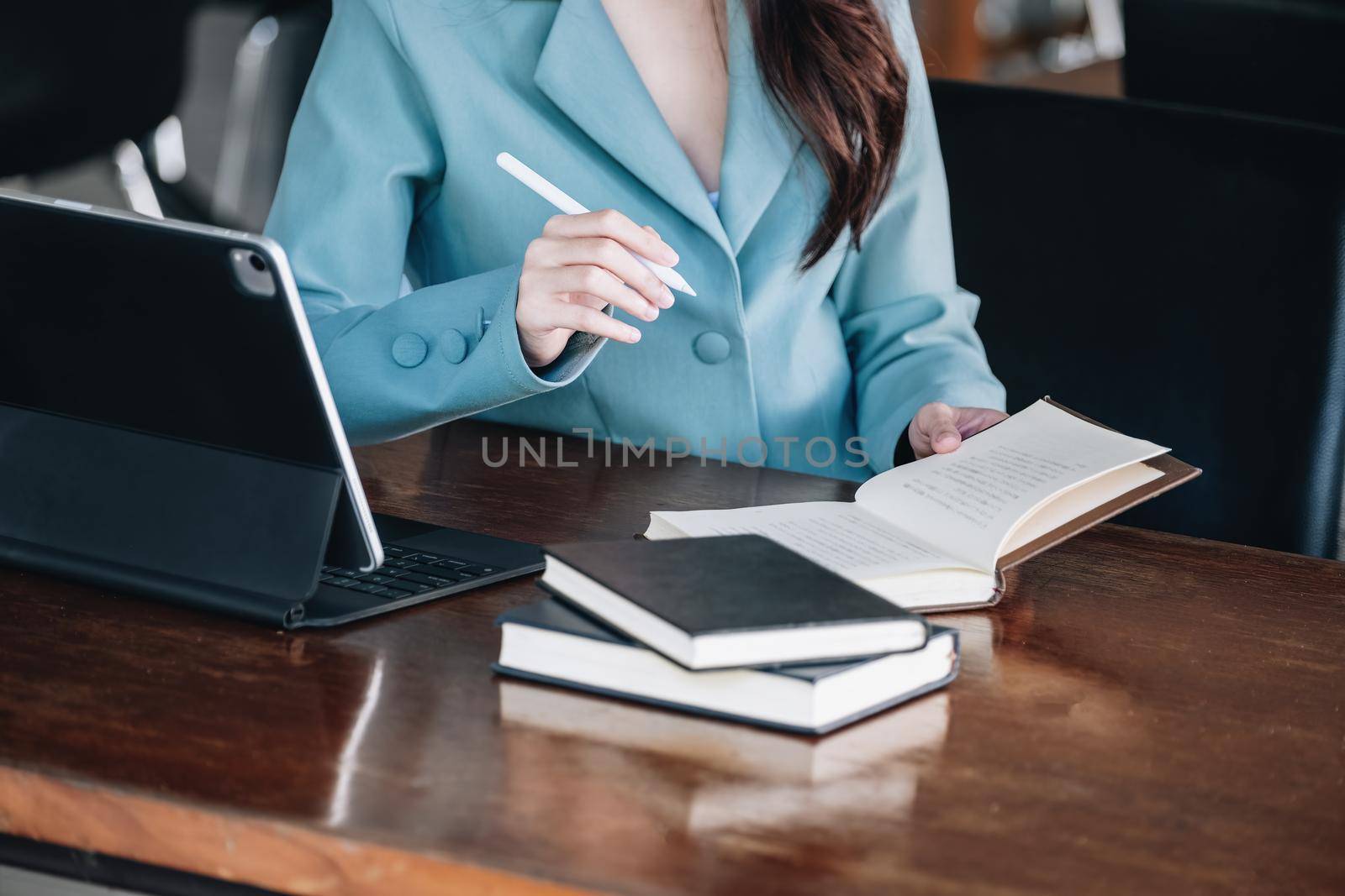 businesswoman showing a smiling face while reading a book developing financial and investing strategies and operating a computer tablet working on a wooden table