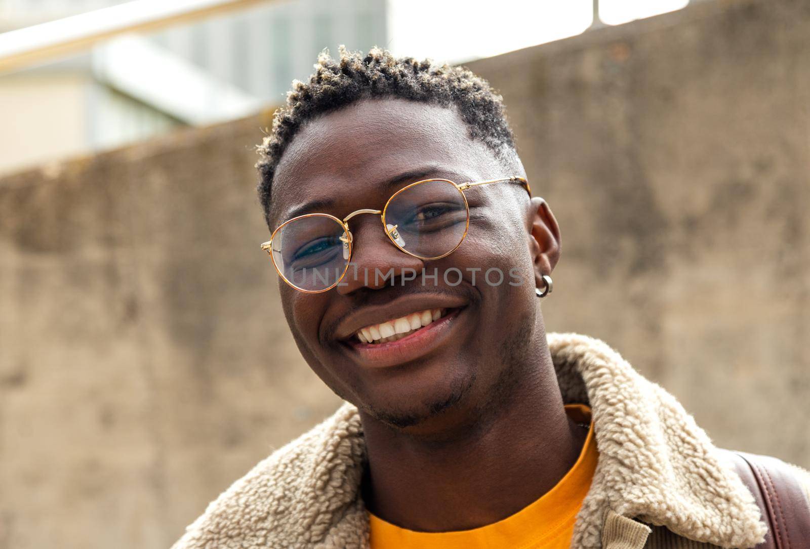 Headshot portrait of attractive, happy african american male gen z college student looking at camera smiling. Gen z lifestyle concept.