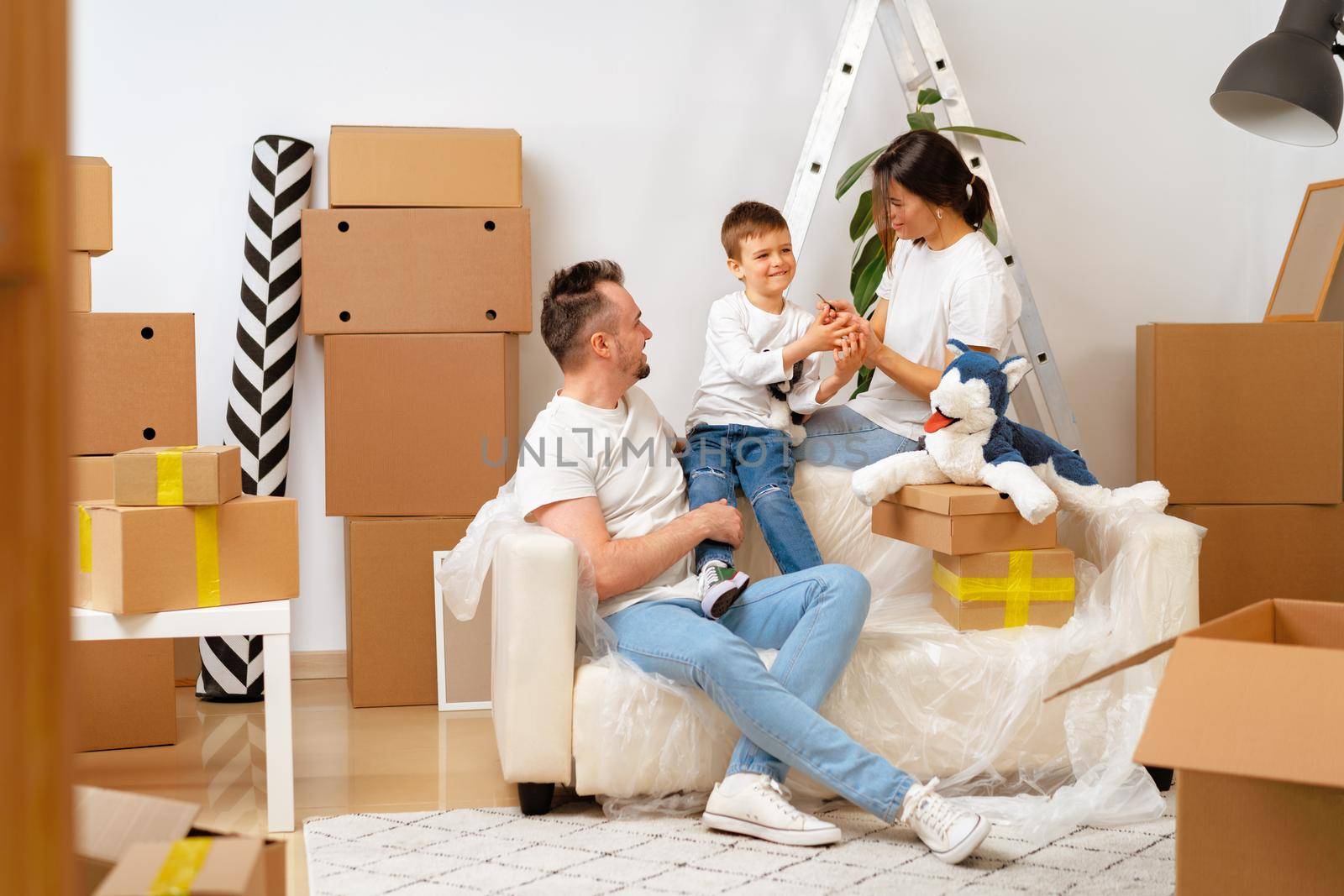 Parents and son packing boxes and moving into a new home by Fabrikasimf