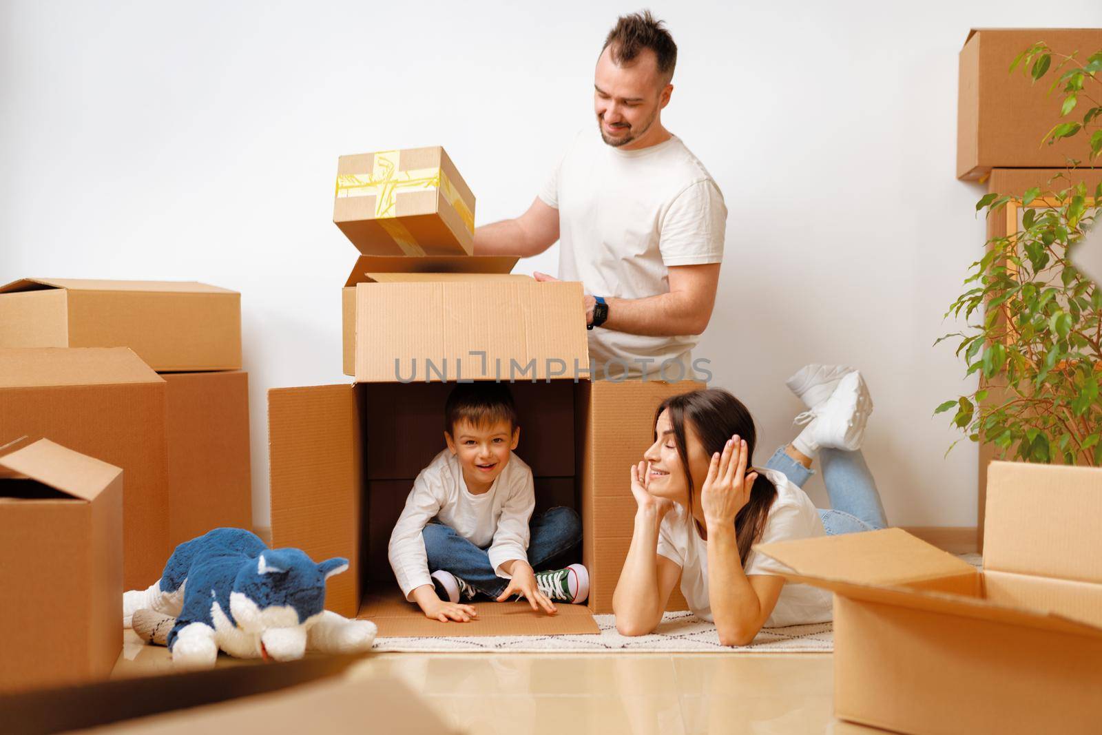 Young parents and son having fun during moving day to new house by Fabrikasimf