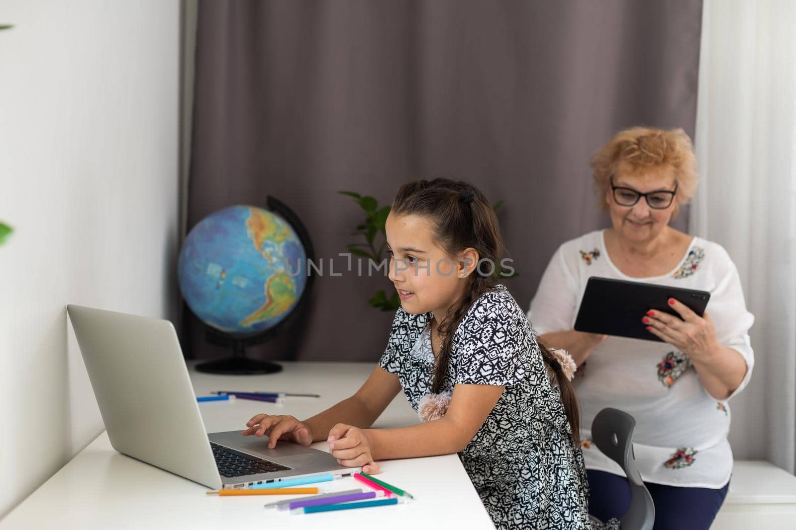 Happy grandmother and her granddaughter having video chat via laptop together at home