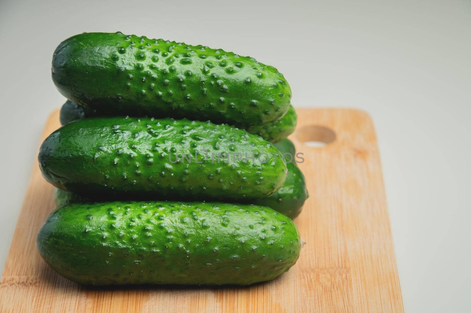 Fresh cucumbers on a wooden cutting board. Vegetables on the kitchen table.