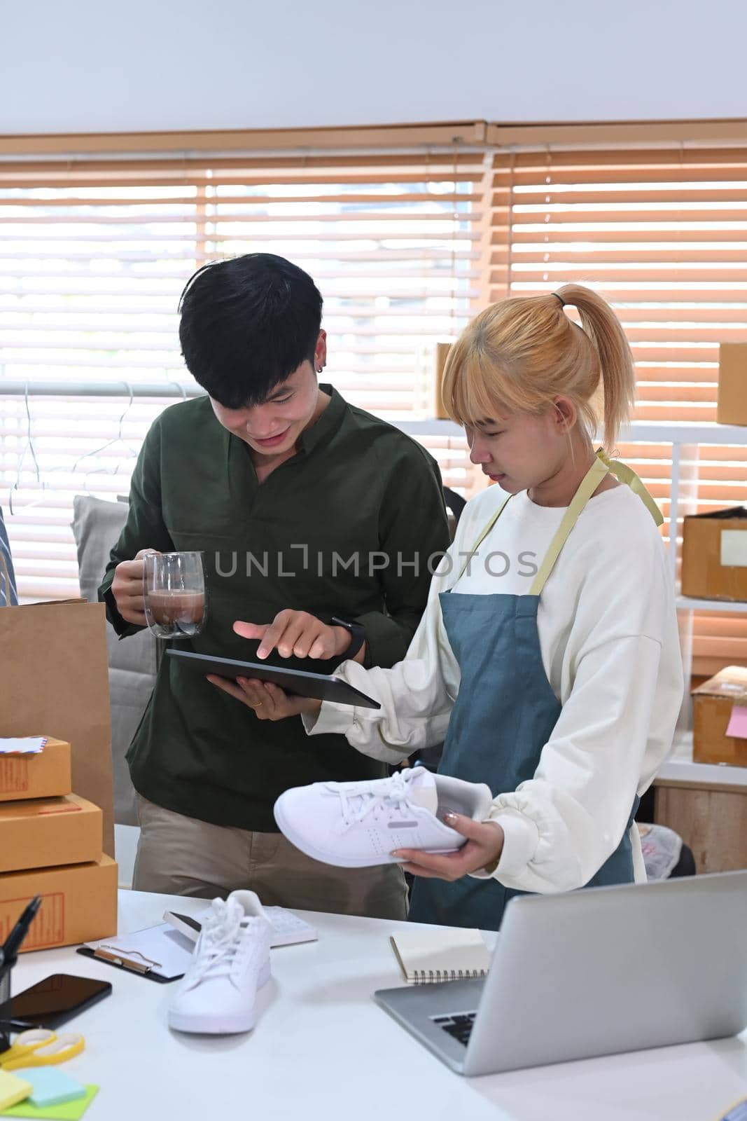 Young asian business couple receive order from customer at their home office.