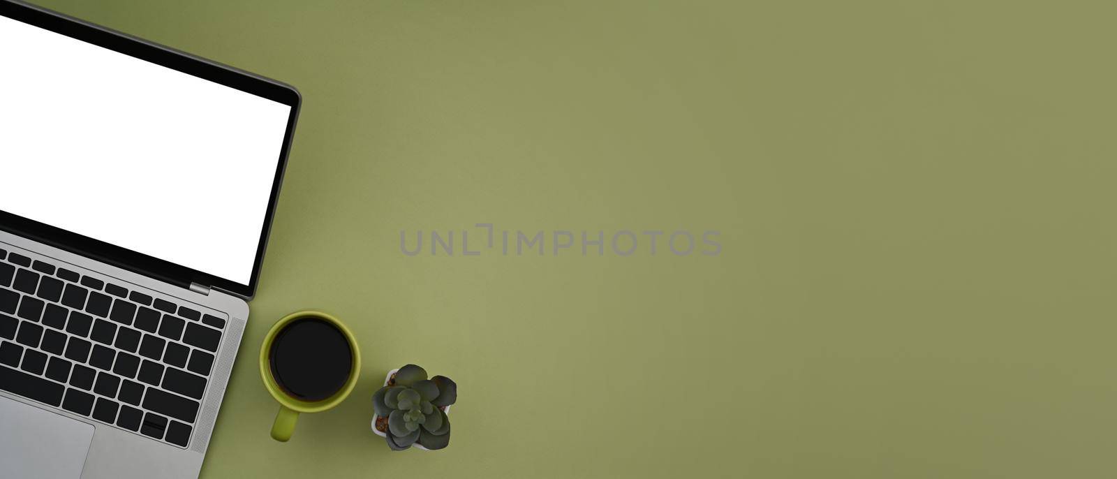 Mockup computer laptop and coffee cup on green background with copy space. by prathanchorruangsak