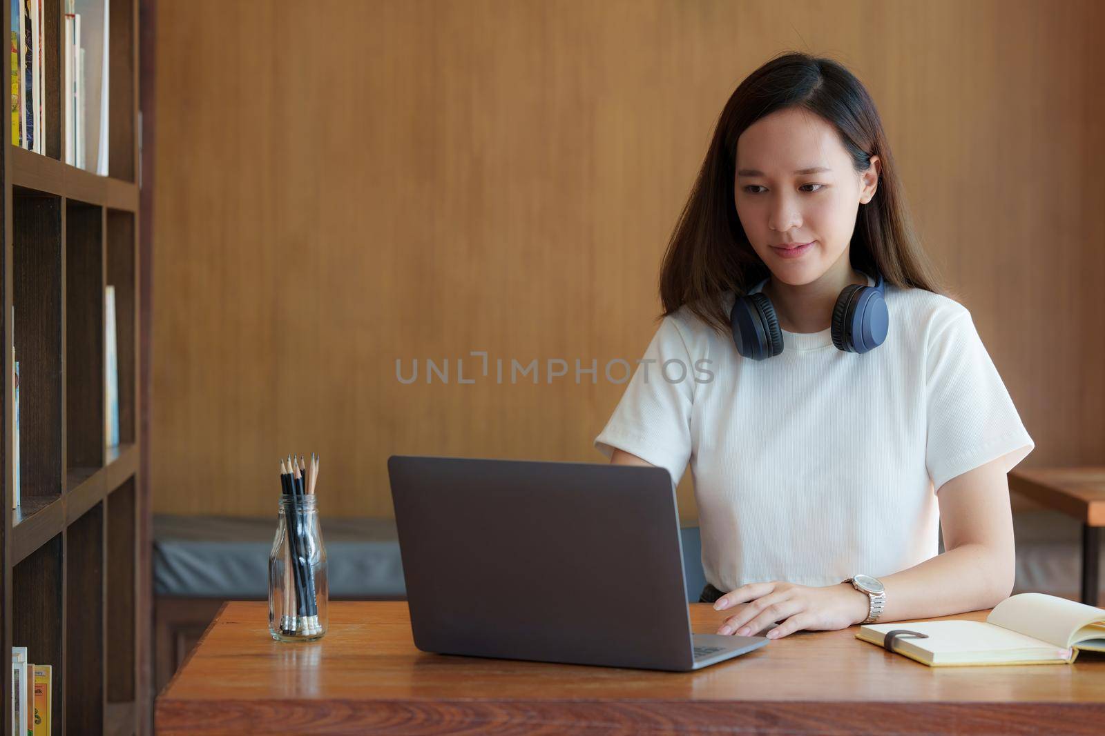 Image of Young woman with a headset working online on laptop computer. studying or working from home online concept