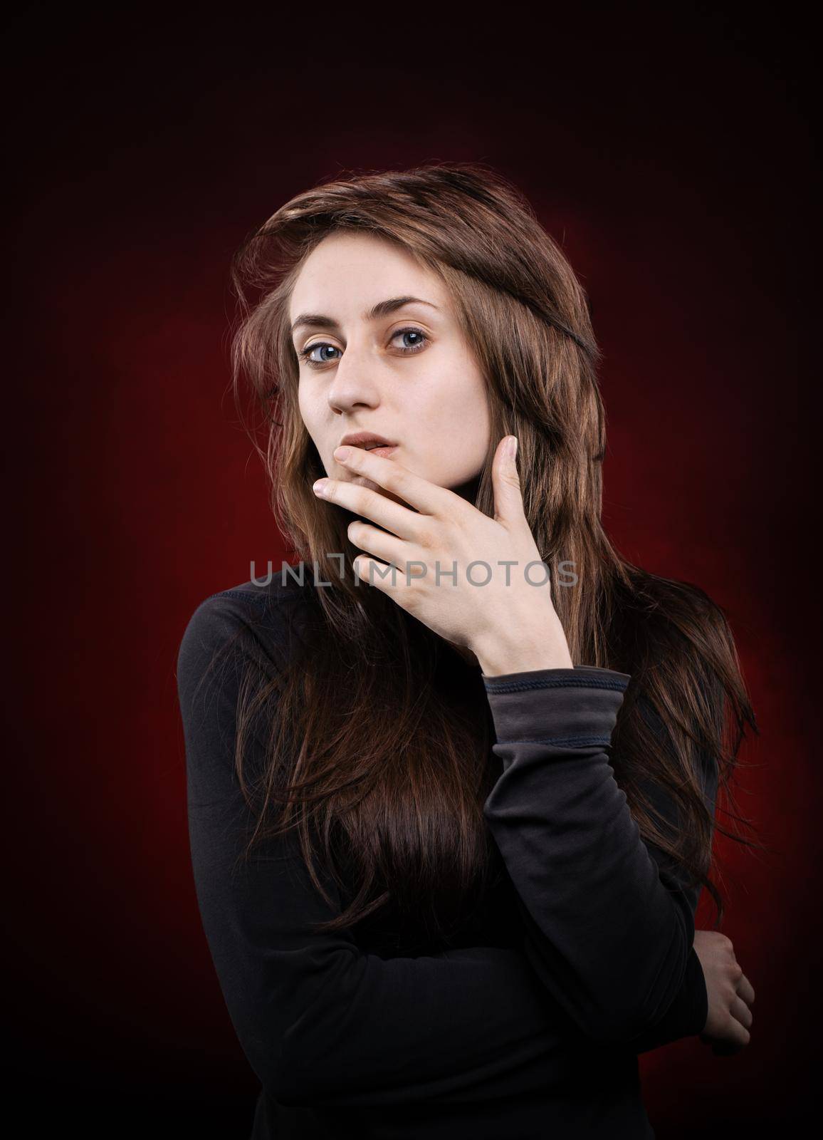 Teenage girl portrait with hands near the face. Fashion, portrait and people concept. Portrait of a young emotional woman on a dark background