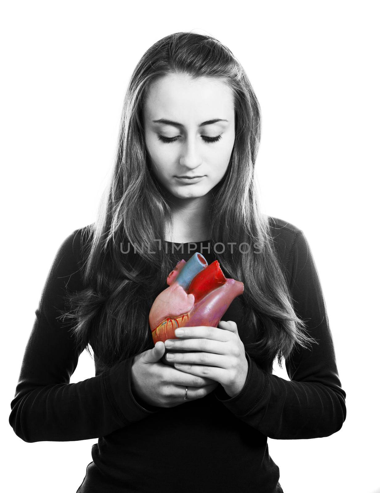 Young woman with heart in hand. Black and white image with local color on the heart