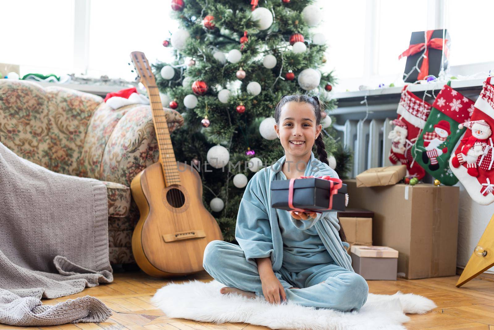 Merry Christmas and Happy Holidays Cute little child girl is decorating the Christmas tree indoors