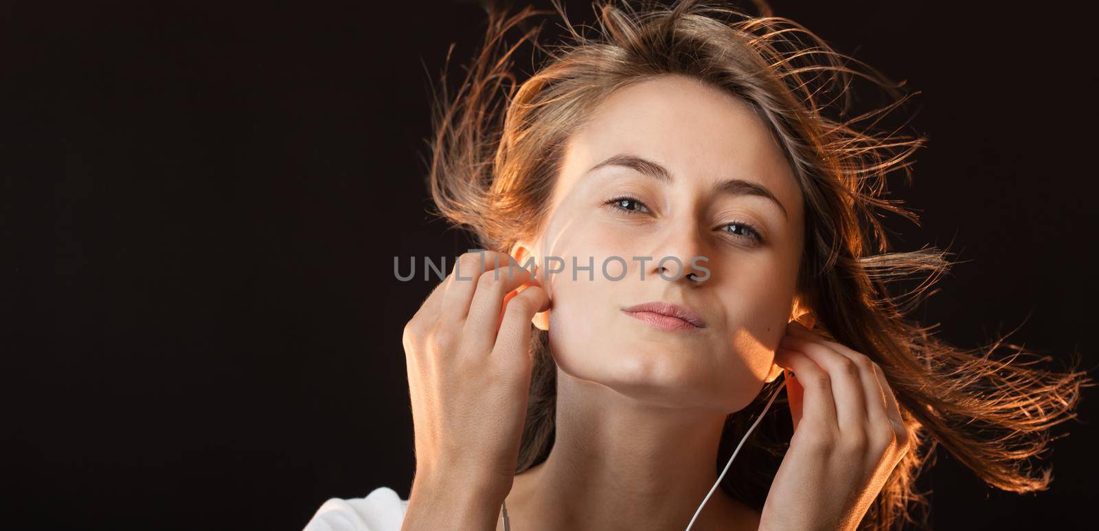 Beautiful Woman Listening Music on a dark background with copy-space