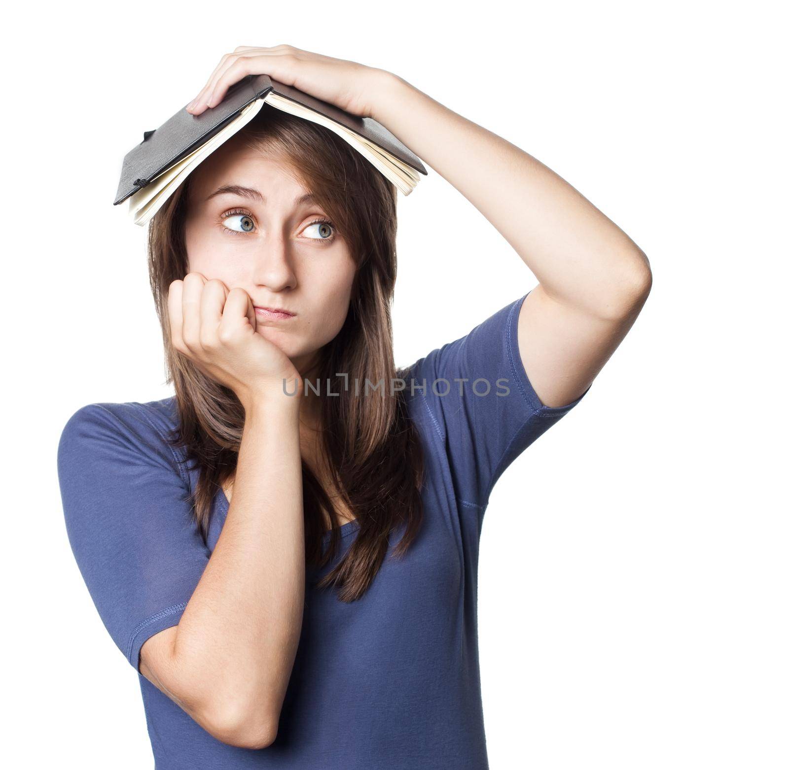 Education. Tired girl holds a notebook on her head on a white background with copyspace
