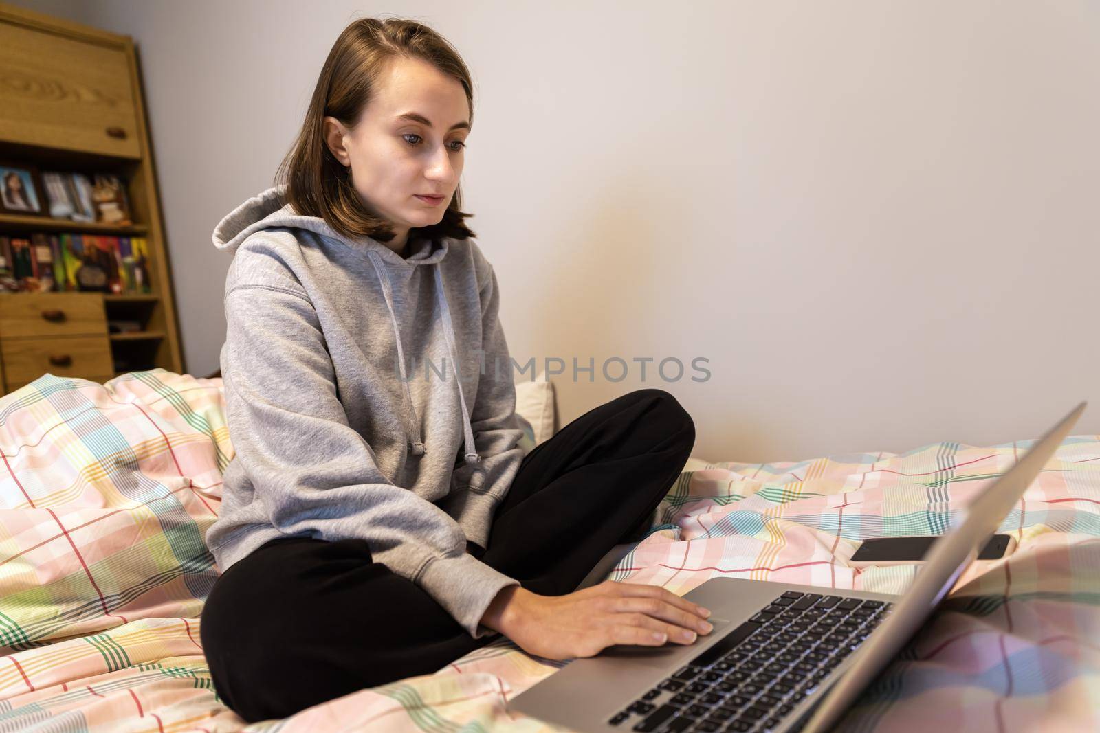 Home office and remote work concept. A young woman works on a computer remotely at home while sitting on a couch during the coronavirus pandemic.