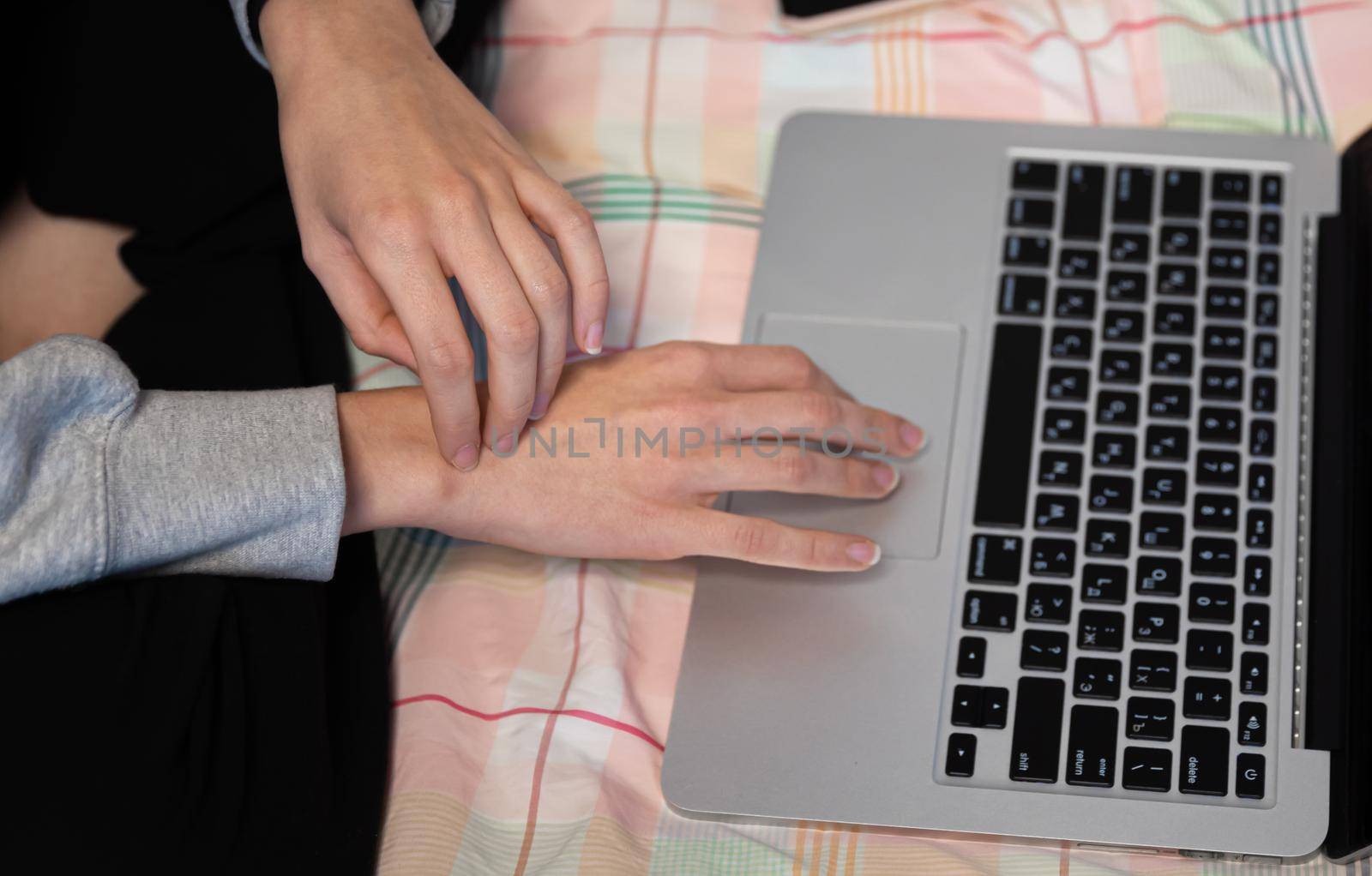 Home office and remote work concept. A young woman works on a computer remotely at home while sitting on a couch during the coronavirus pandemic.