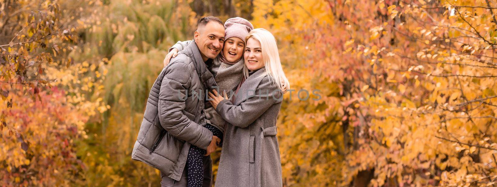 family, childhood, season and people concept - happy family playing with autumn leaves in park.