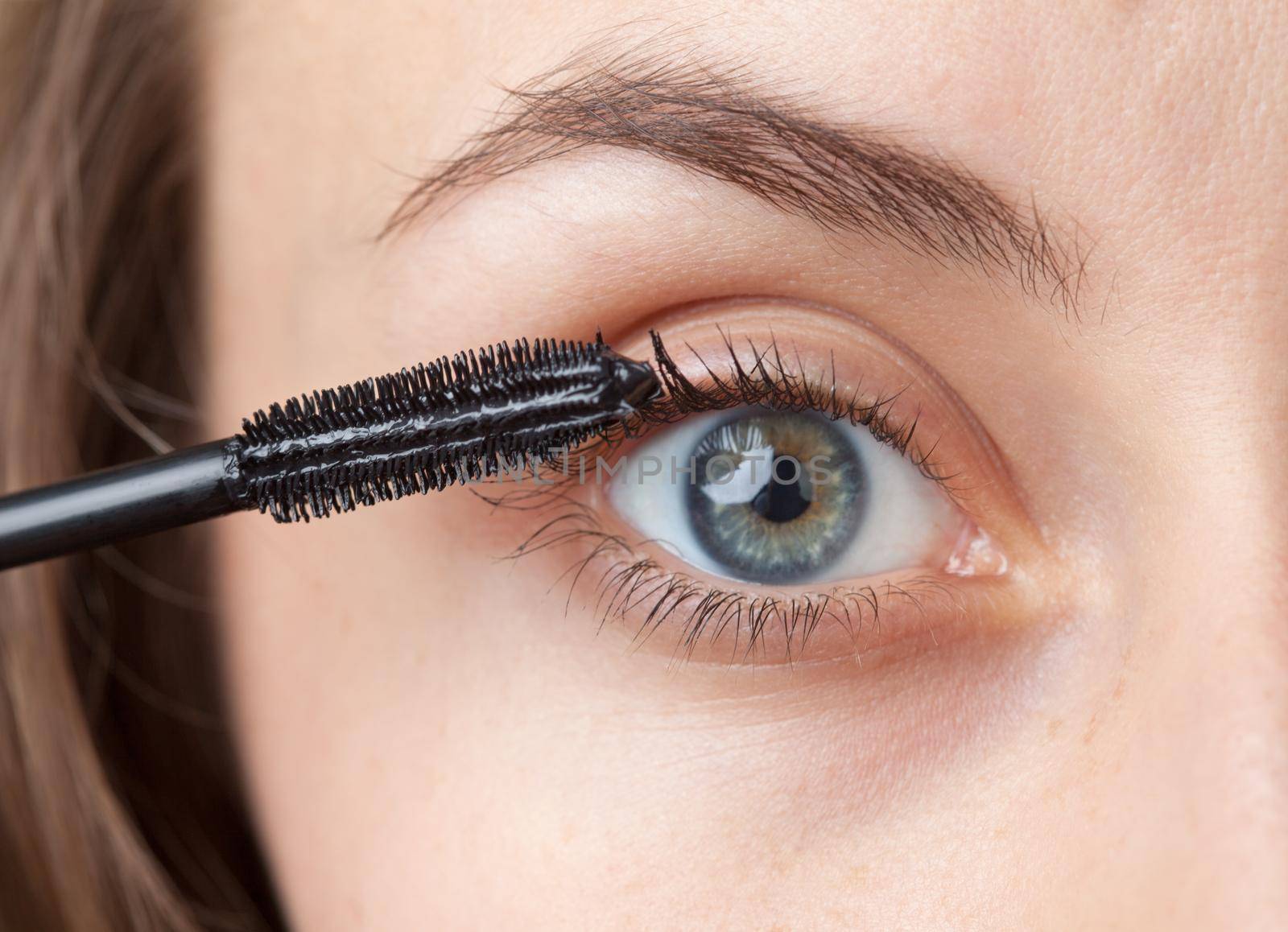 Woman applying mascara on her eyelashes