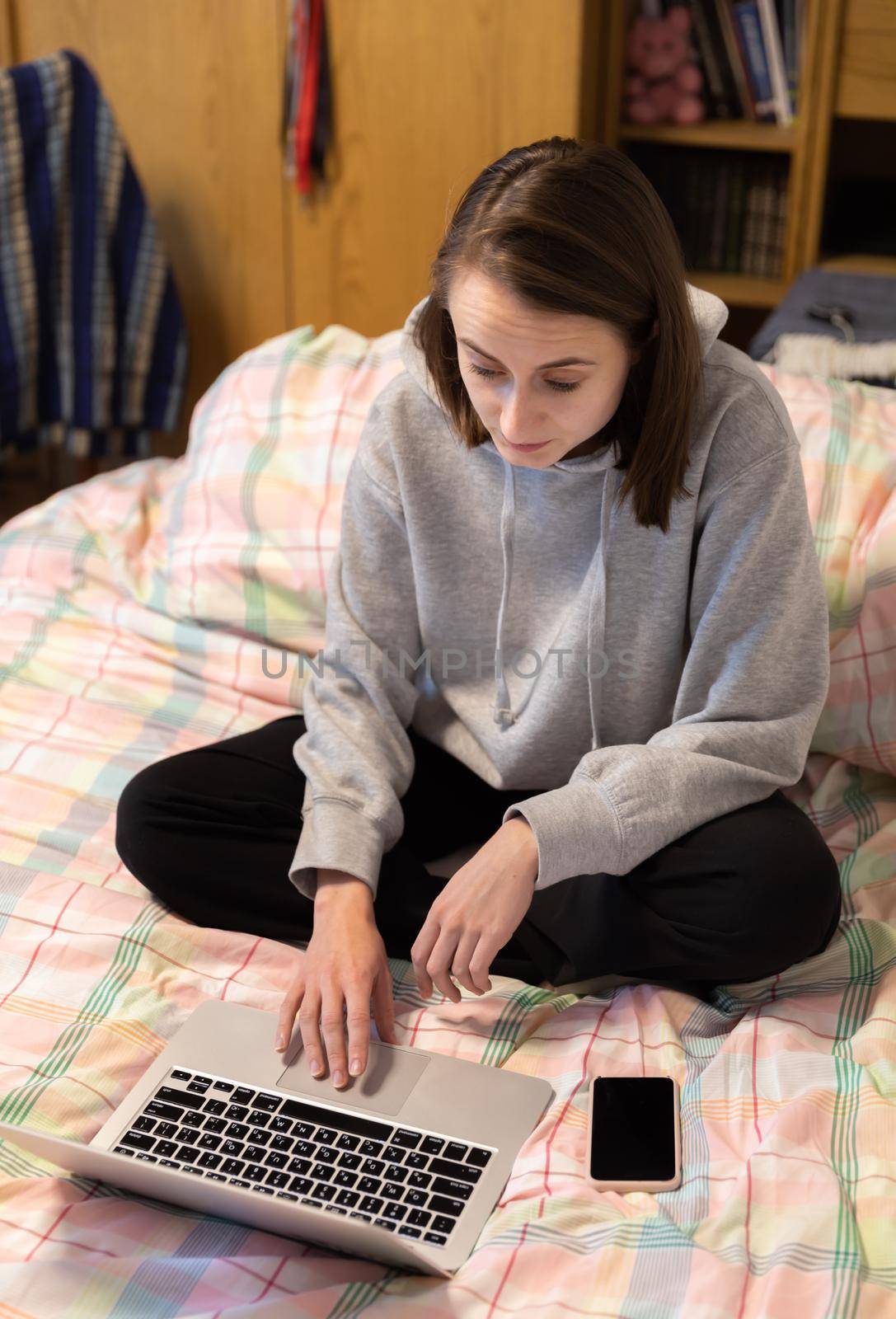 Home office and remote work concept. A young woman works on a computer remotely at home while sitting on a couch during the coronavirus pandemic.