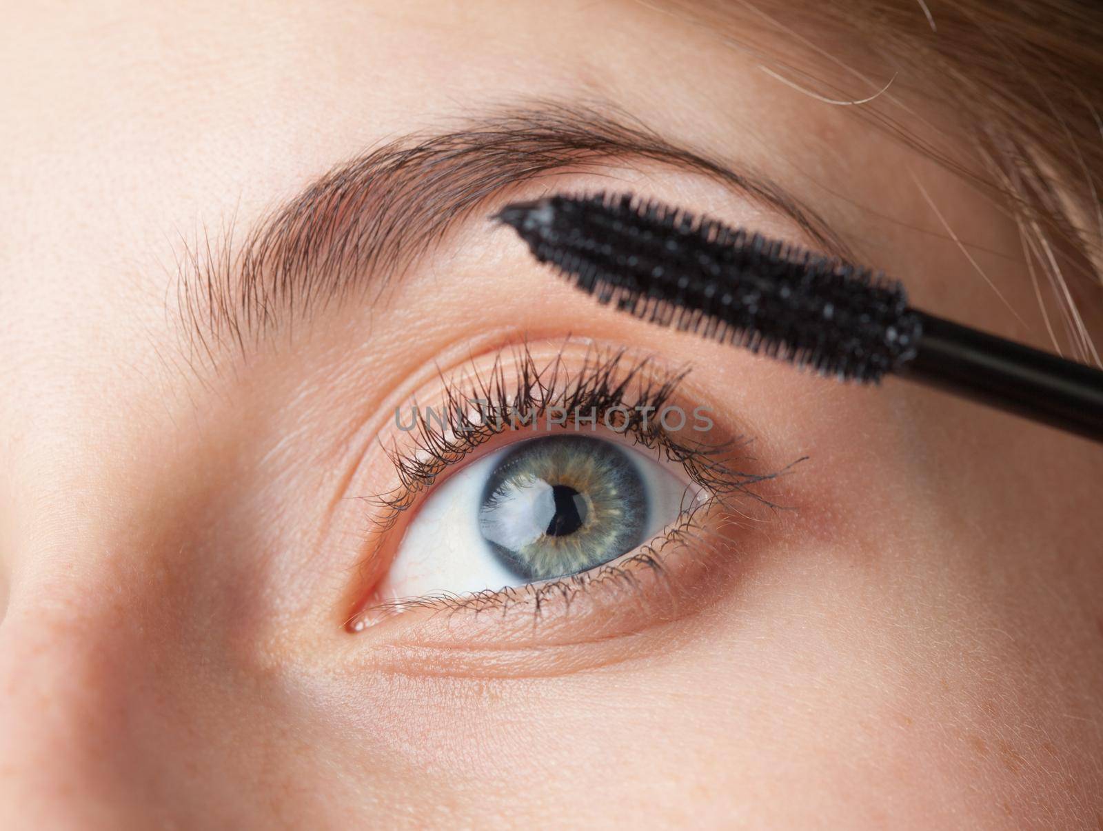 Woman applying mascara on her eyelashes