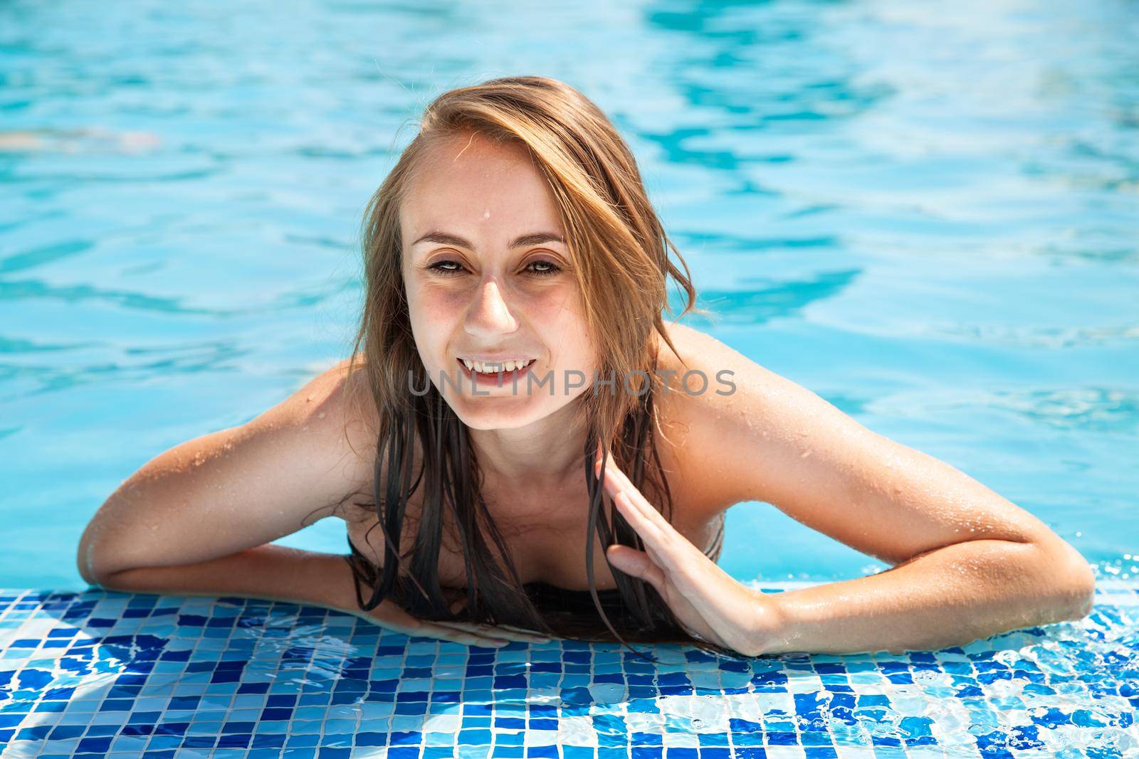 Young beautiful woman sunbathing in the swimming pool