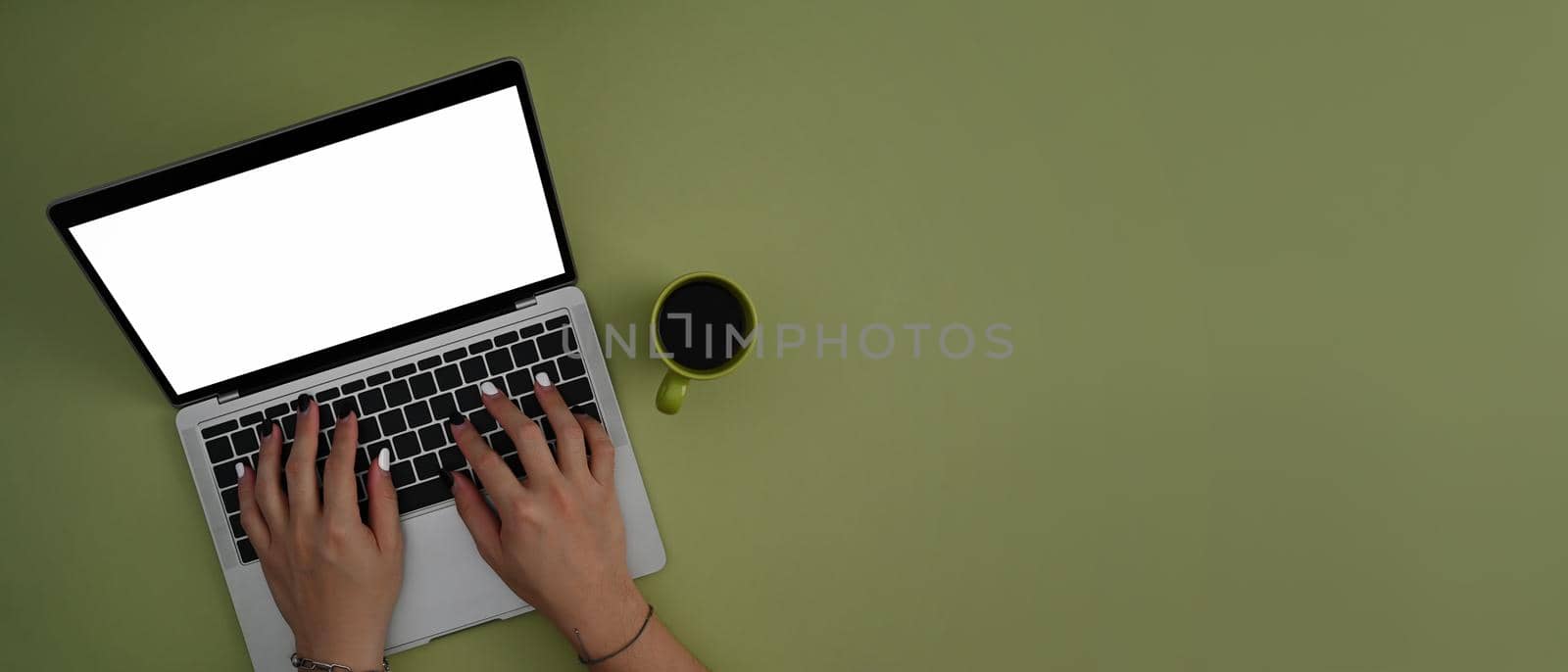 Woman using laptop computer on green background with copy space. Top view.