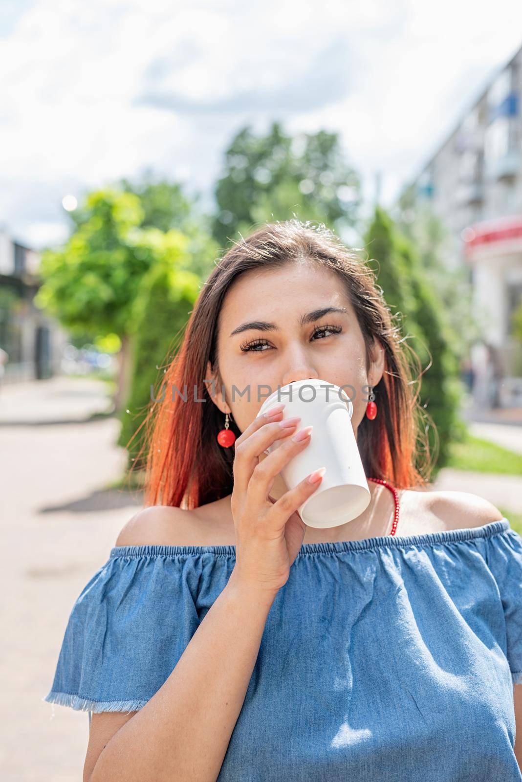 Stylish millennial woman drinking coffee at street cafe in summer by Desperada