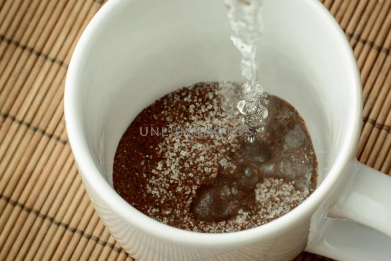 Pouring boiling water to the cap with coffee and sugar