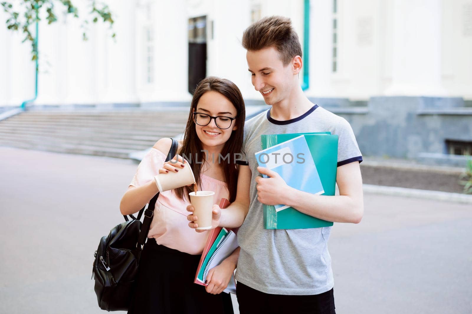 Attractive girl share some coffee with her handsome classmate, ready to help each other in difficult situation. Concept of friendship.
