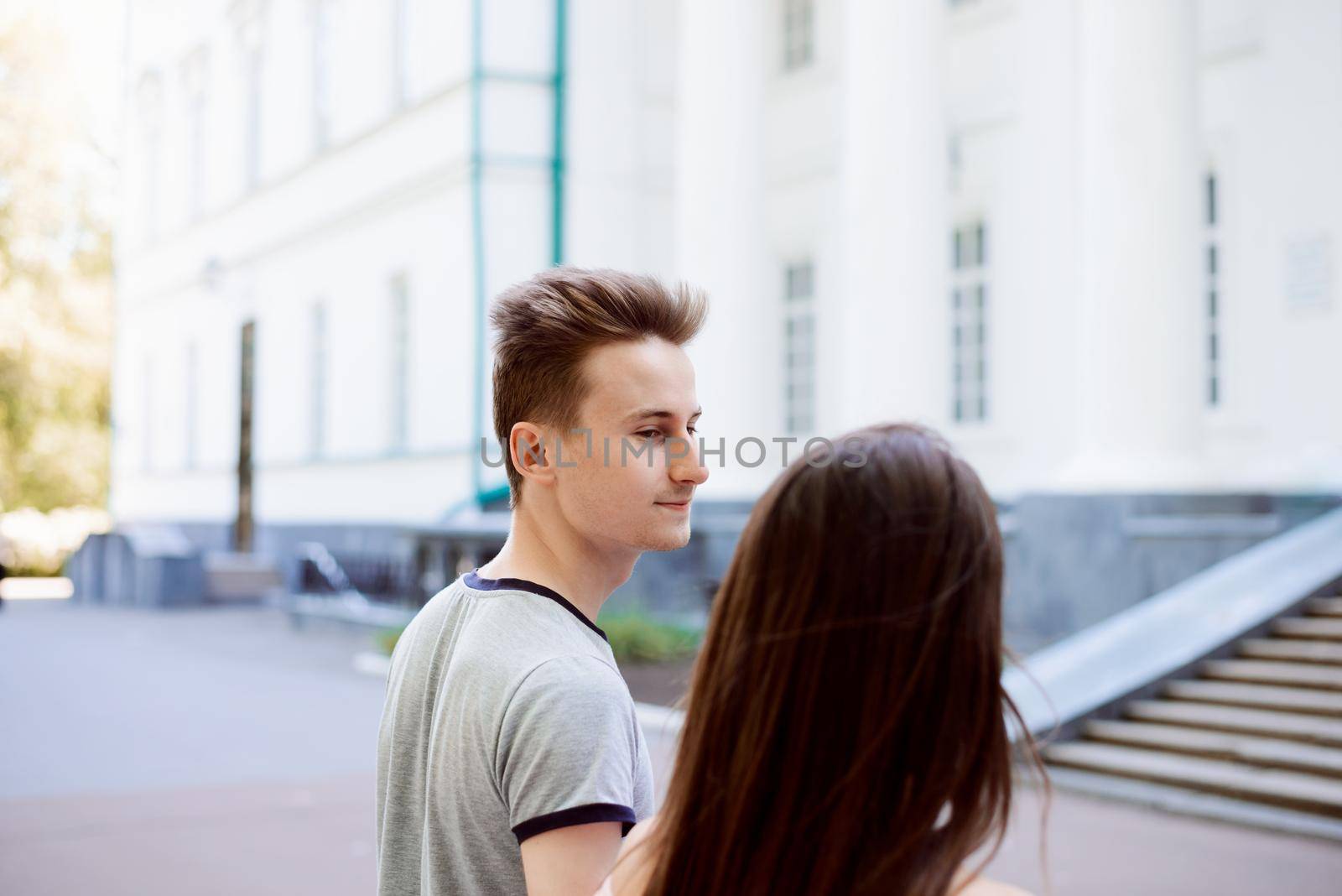 Side photo of a male student looking at her female friend with love in his eyes and heading to the university together