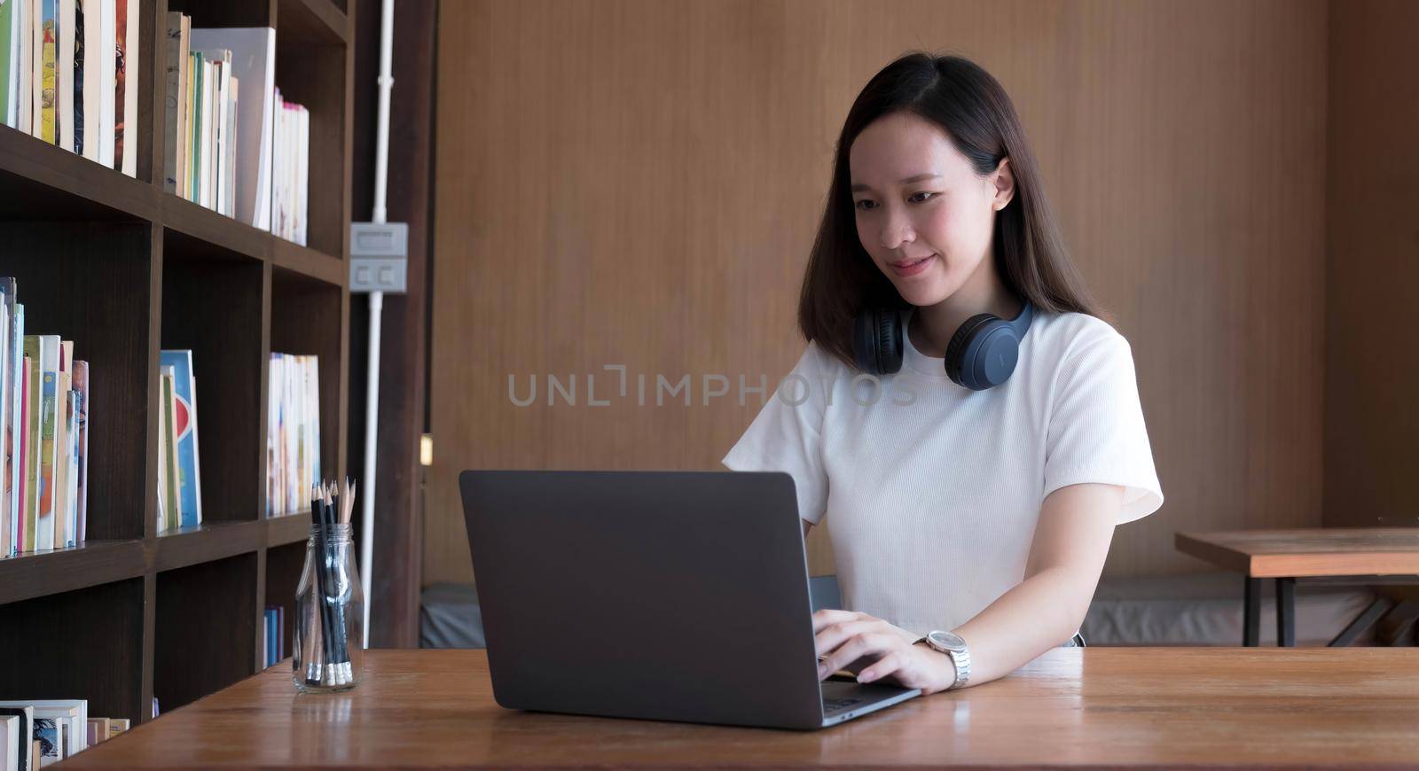 Smart asian young girl student feel satisfied during internet online courses and searching information via laptop computer at home by wichayada