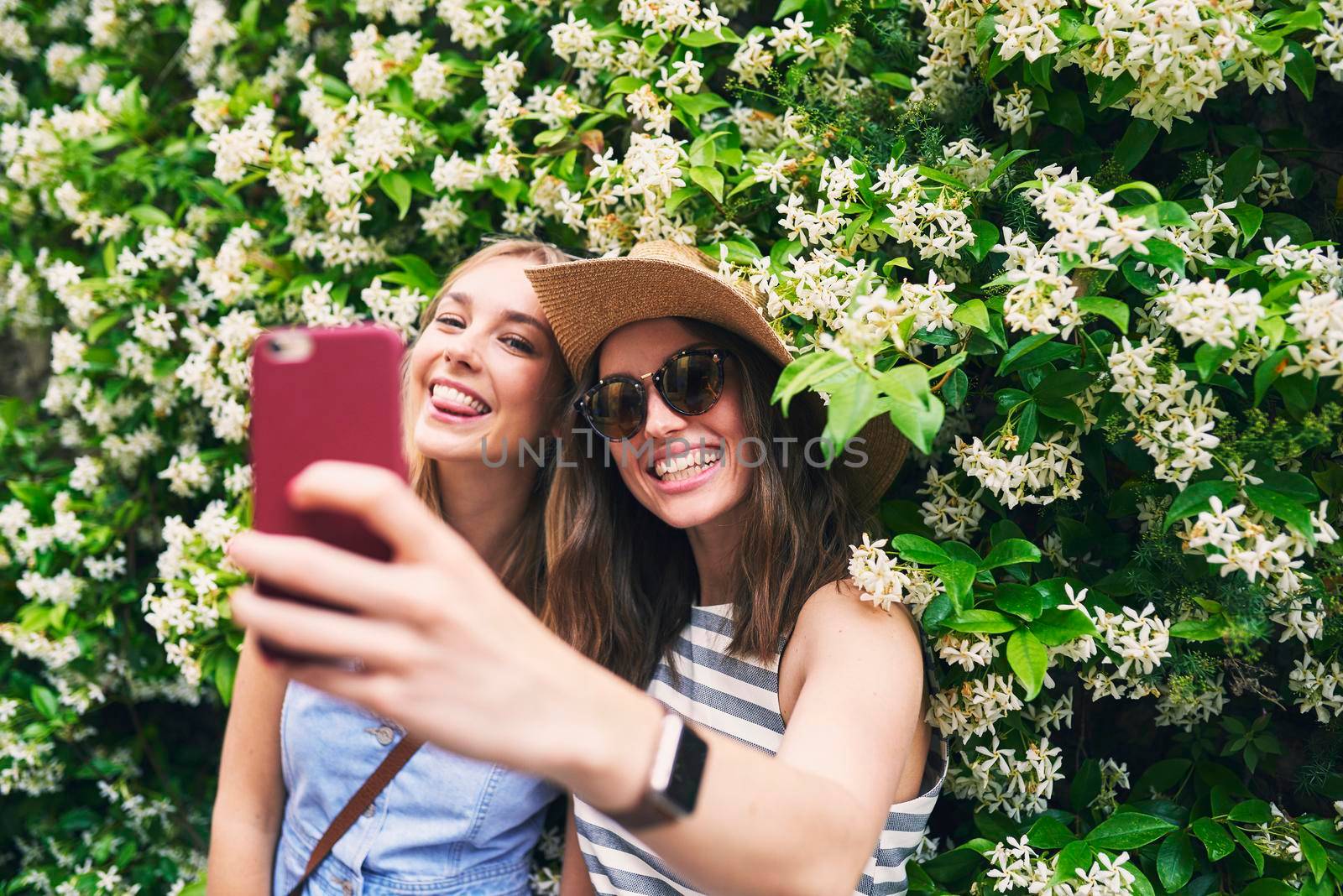 Two friends taking selfies on summer vacation. Girl friends on travel adventure taking photos for social media with smartphone.