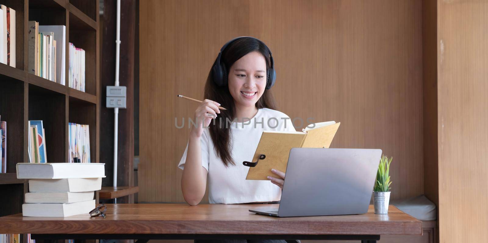 Asian woman wearing headphones study online watching webinar podcast on laptop listening learning education course conference calling, elearning concept..