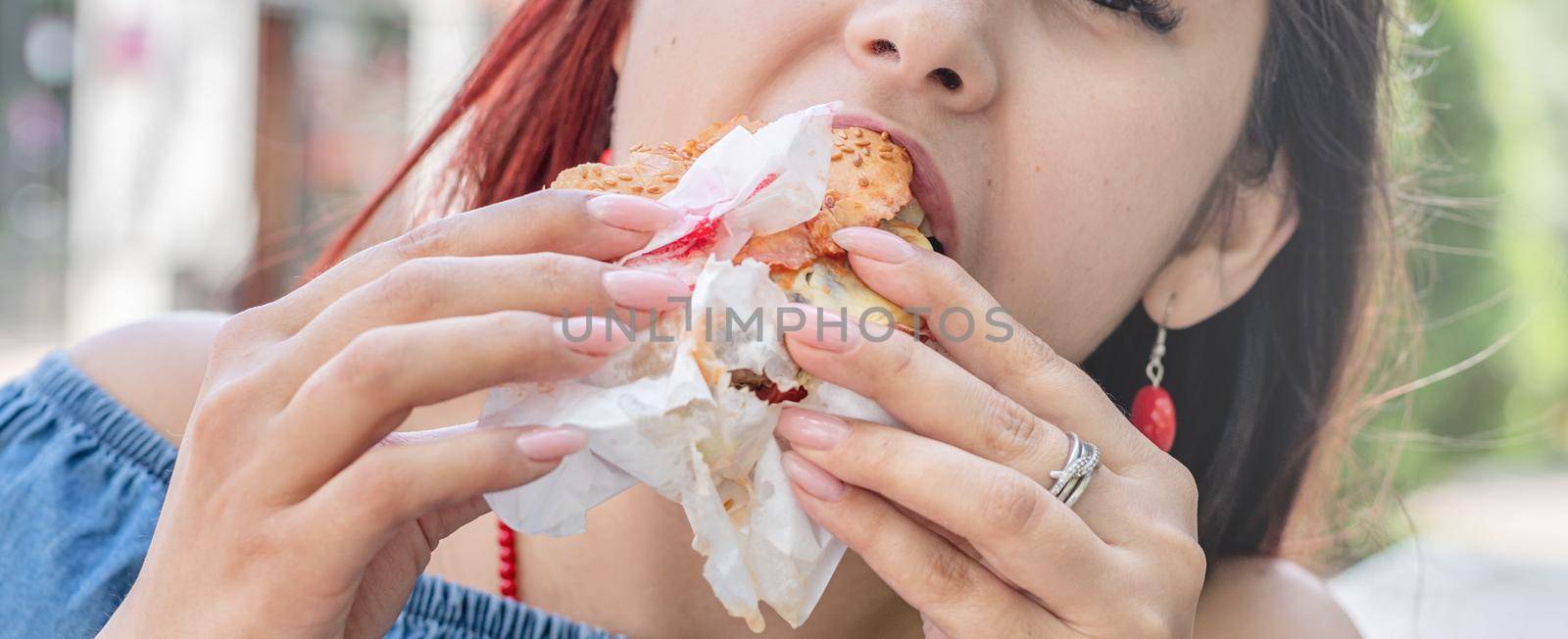 Stylish millennial woman eating burger at street cafe in summer by Desperada