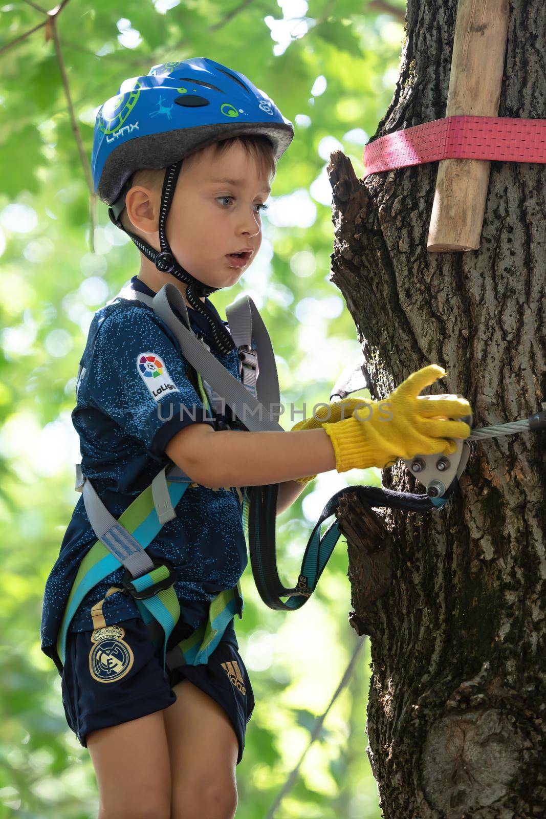 UZHHOROD, UKRAINE - Jul 23, 2020: Extreme sport in adventure park. Young boy passing the cable route high among trees