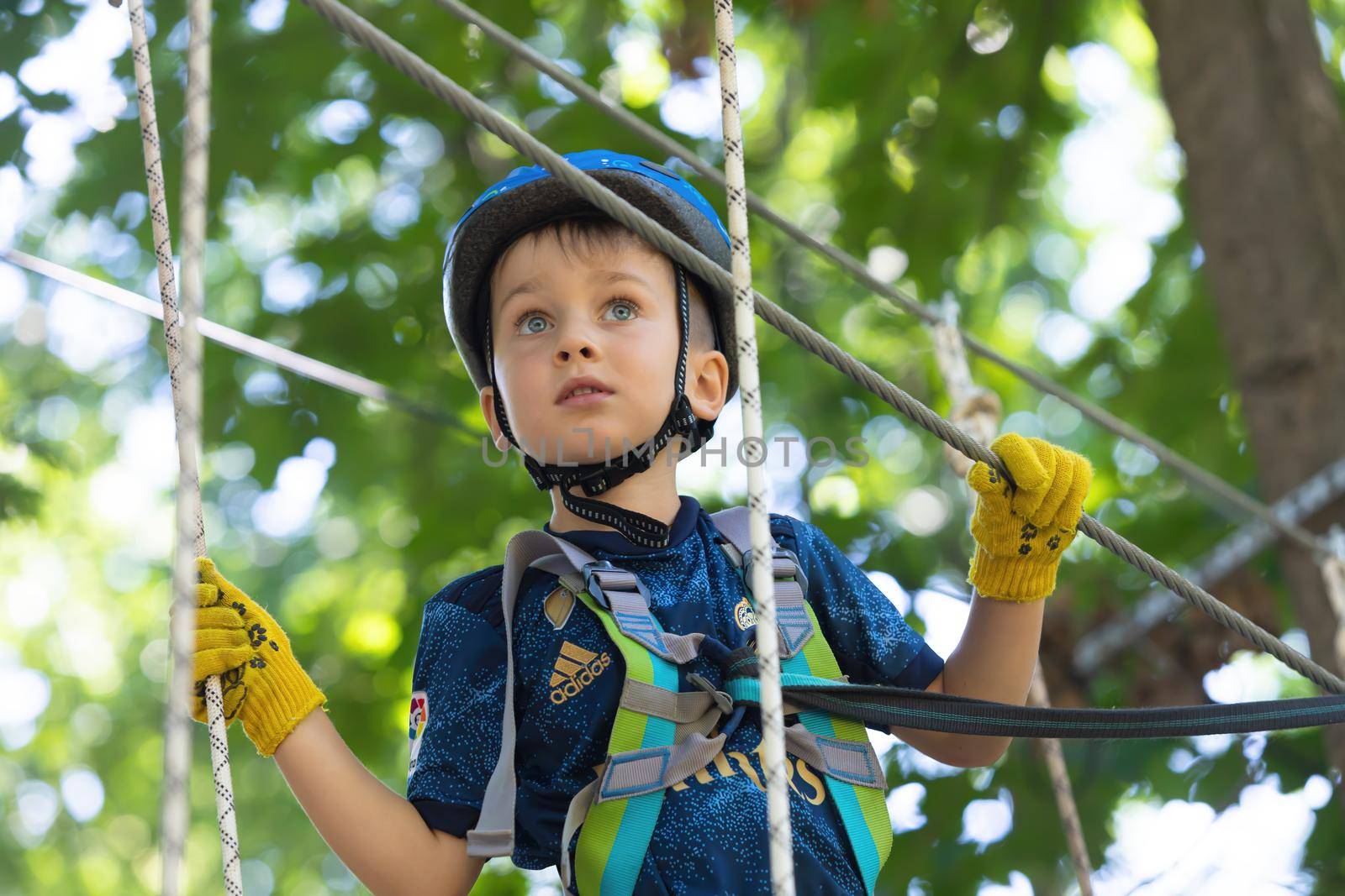 UZHHOROD, UKRAINE - Jul 23, 2020: Extreme sport in adventure park. Young boy passing the cable route high among trees