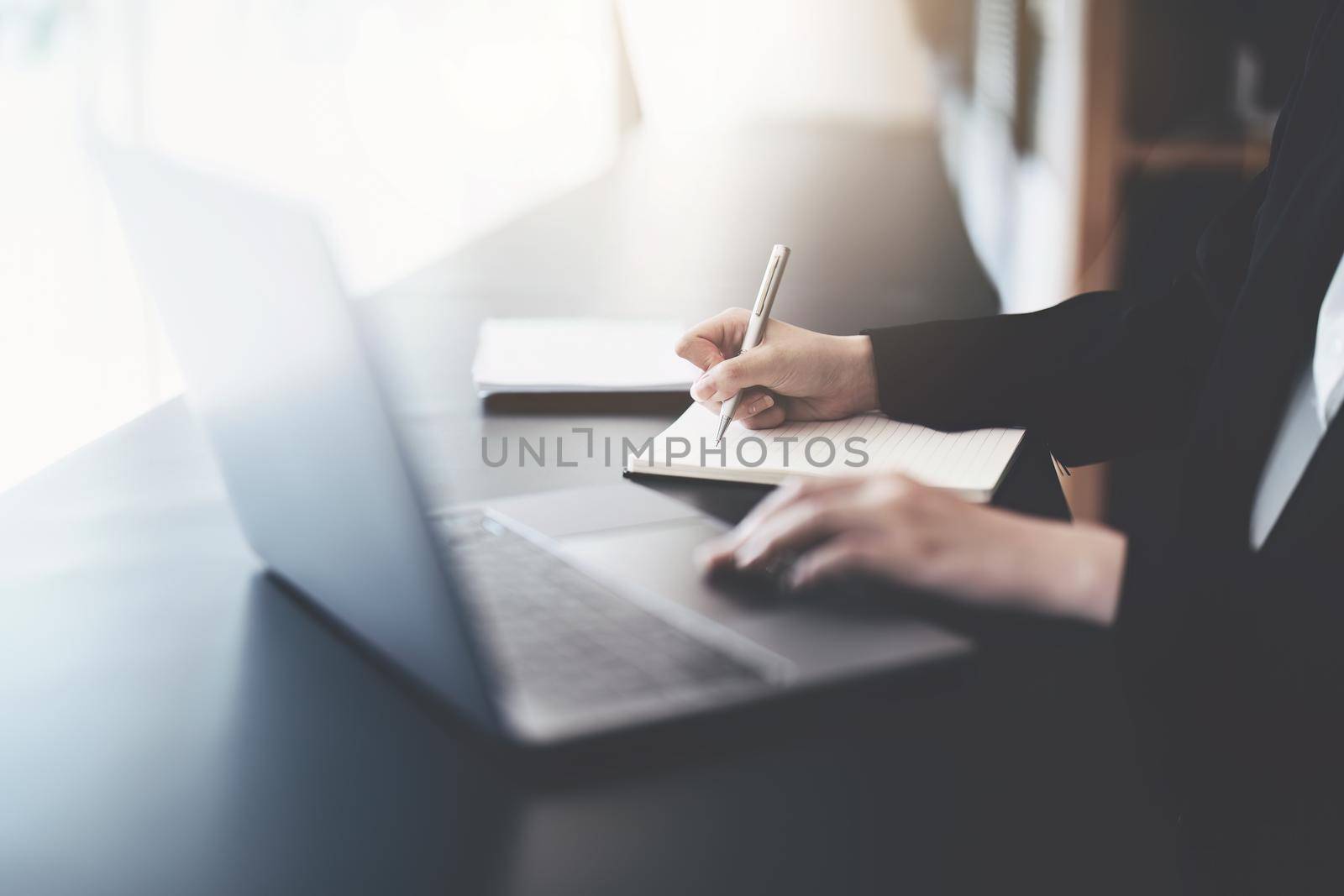 usiness woman writing marketing plan in notebook ready to use computer in office.