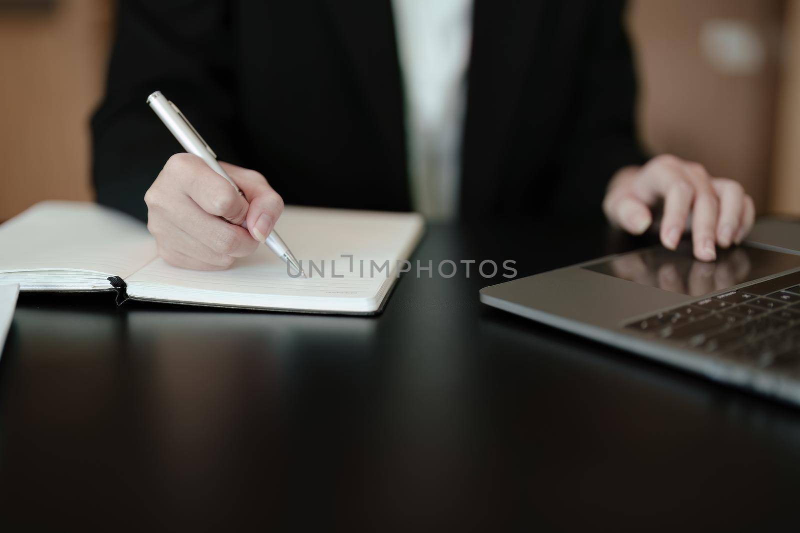 usiness woman writing marketing plan in notebook ready to use computer in office.