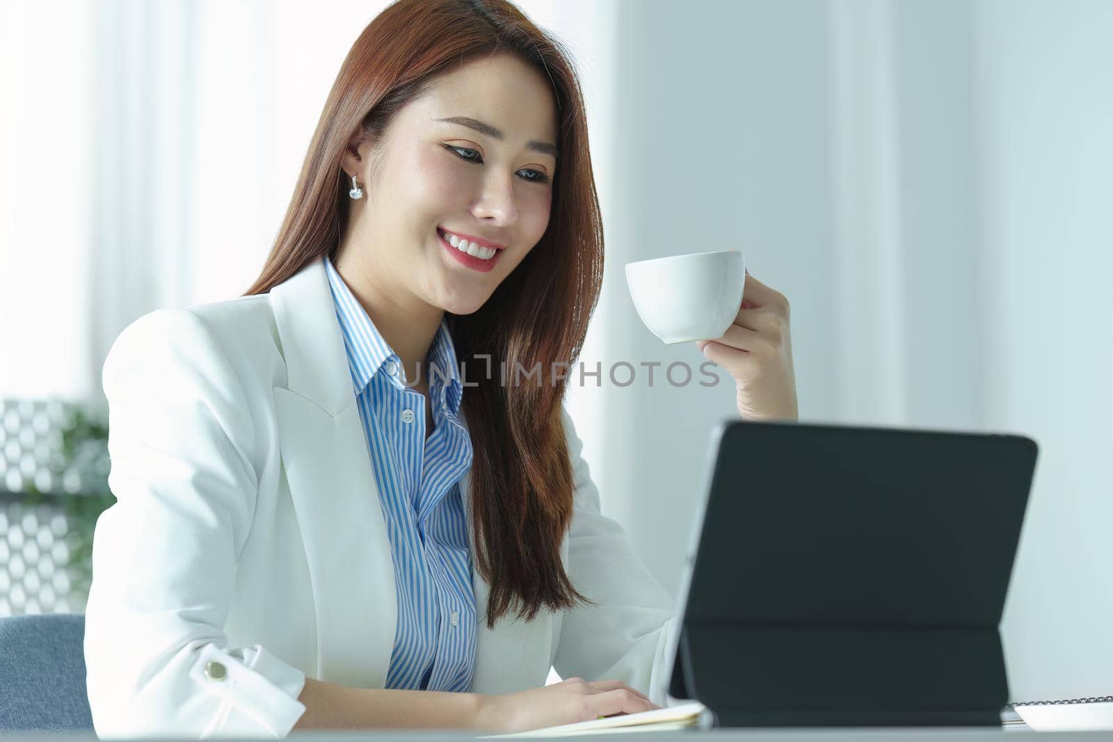 Portrait of an Asian businesswoman or business owner taking a coffee break while working in the office.