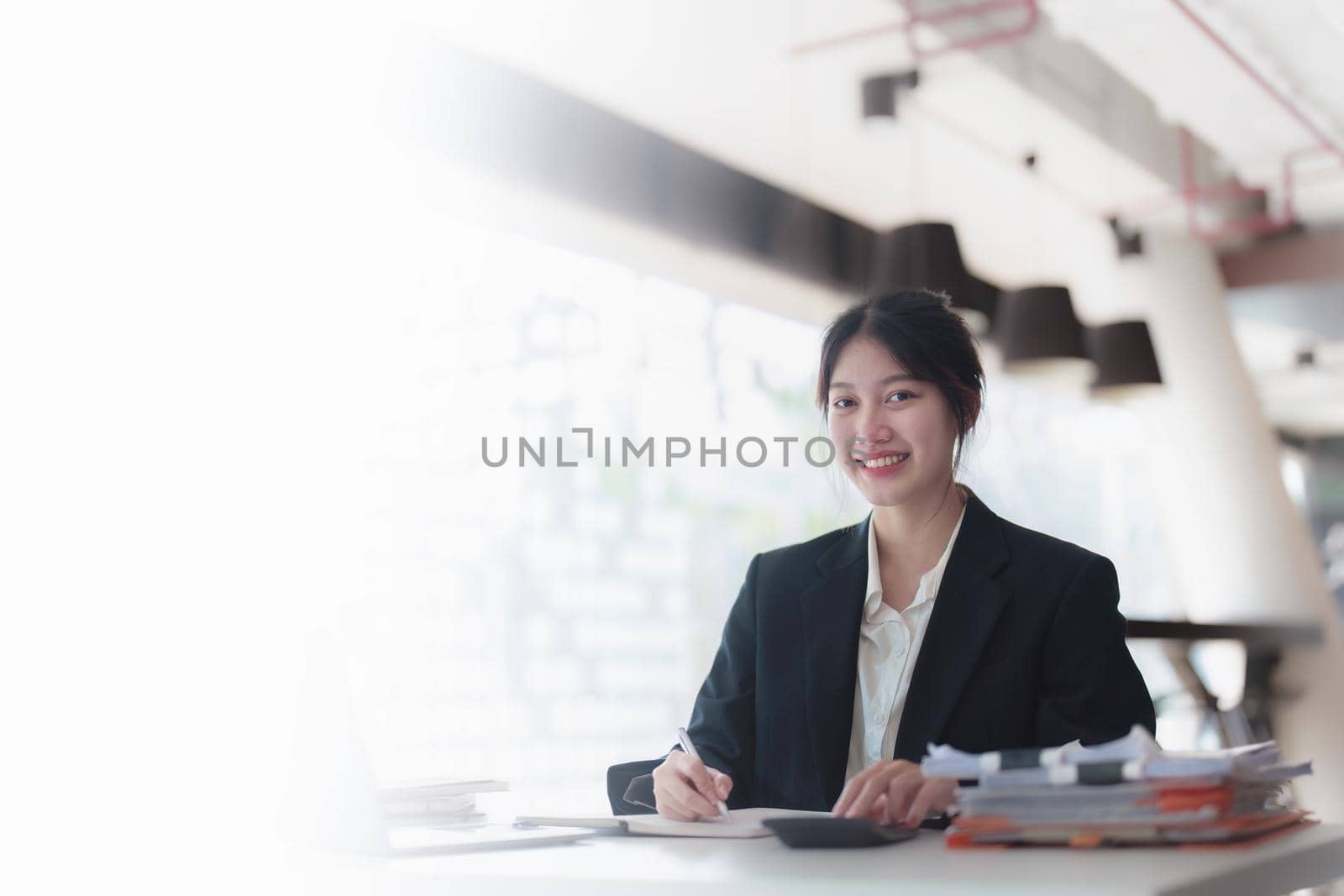 Portrait of an Asian businesswoman working with a happy smile in the office by Manastrong