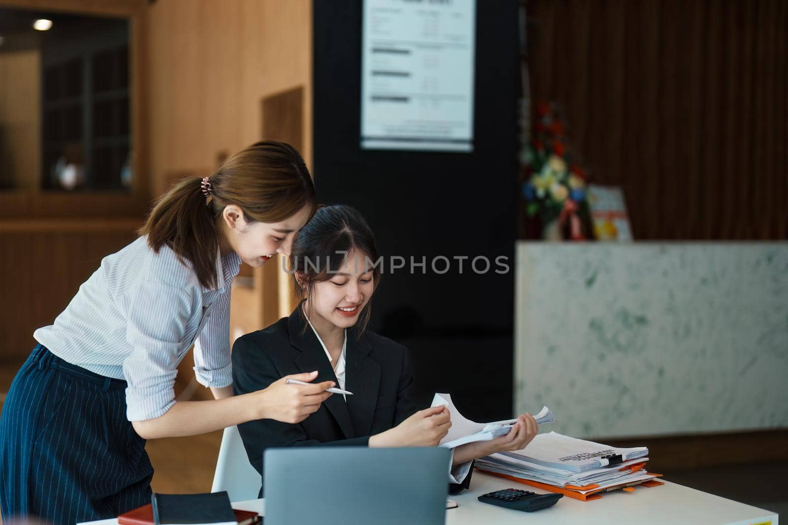 A portrait of two young Asian businesswoman plan marketing strategies and investments to profit from their clients by Manastrong