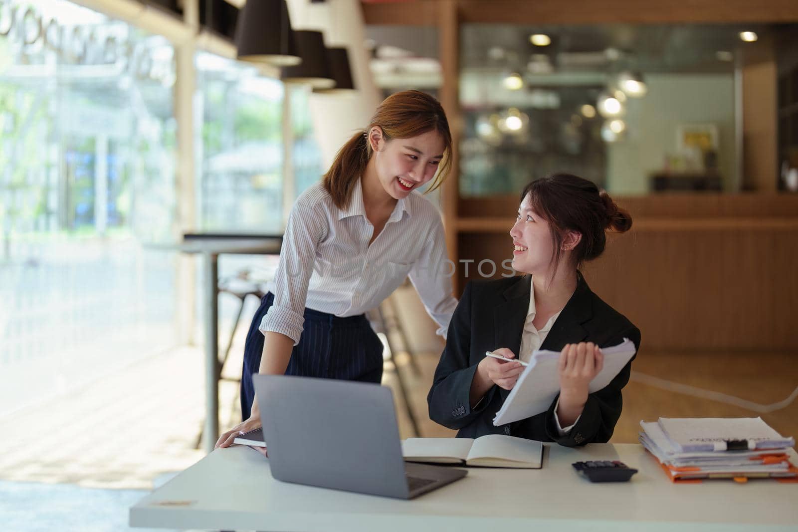 A portrait of two young Asian businesswoman plan marketing strategies and investments to profit from their clients by Manastrong