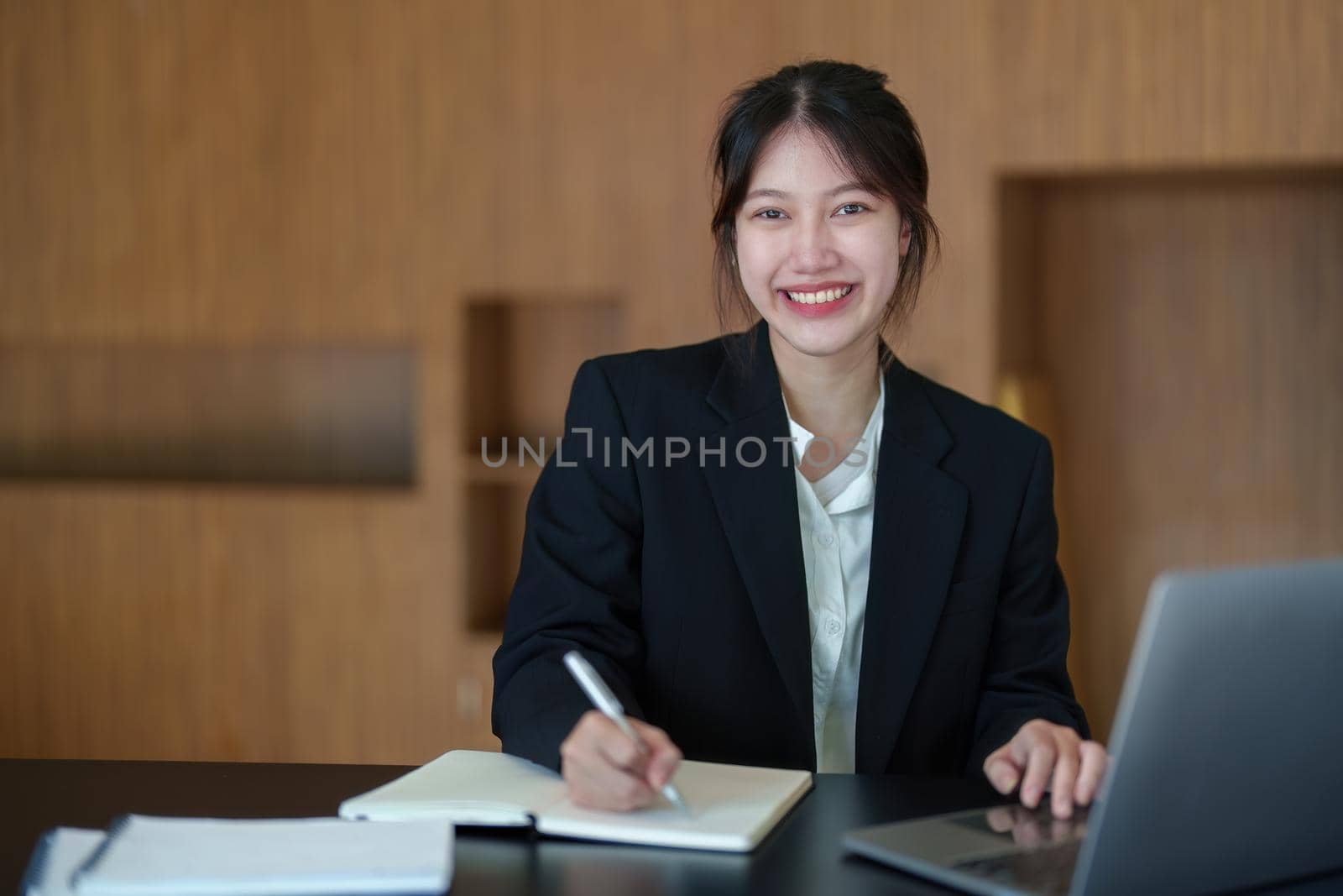 Portrait of an Asian businesswoman working with a happy smile in the office by Manastrong