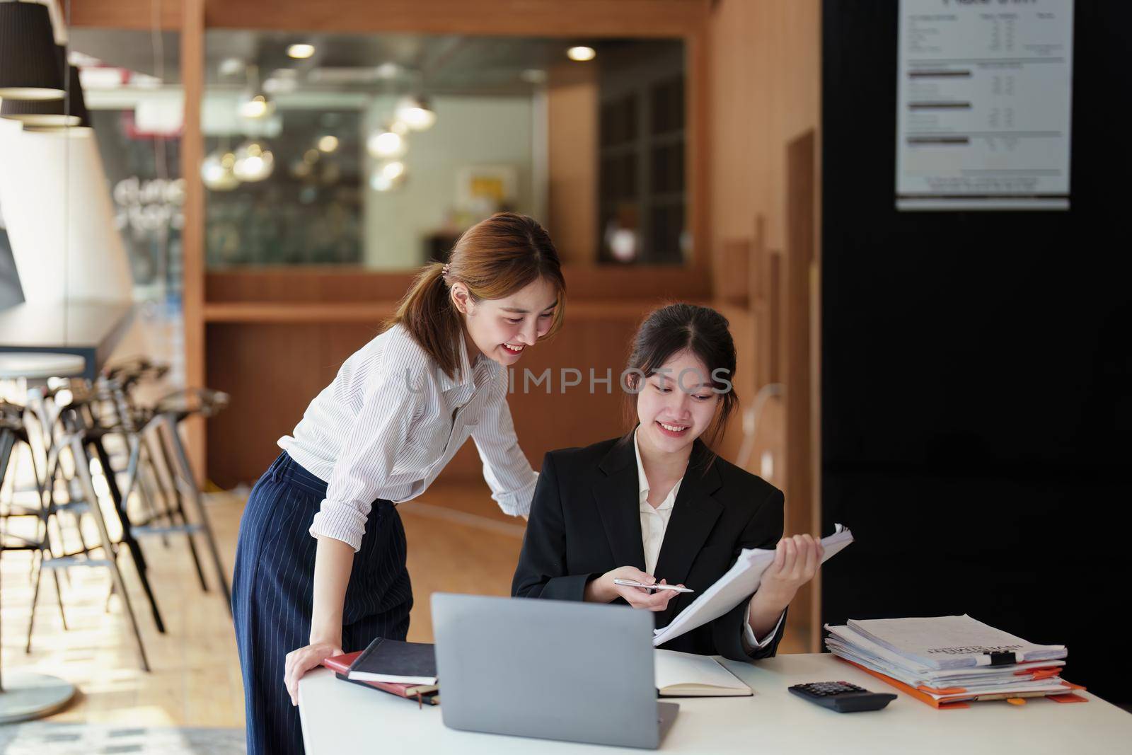 A portrait of two young Asian businesswoman plan marketing strategies and investments to profit from their clients.