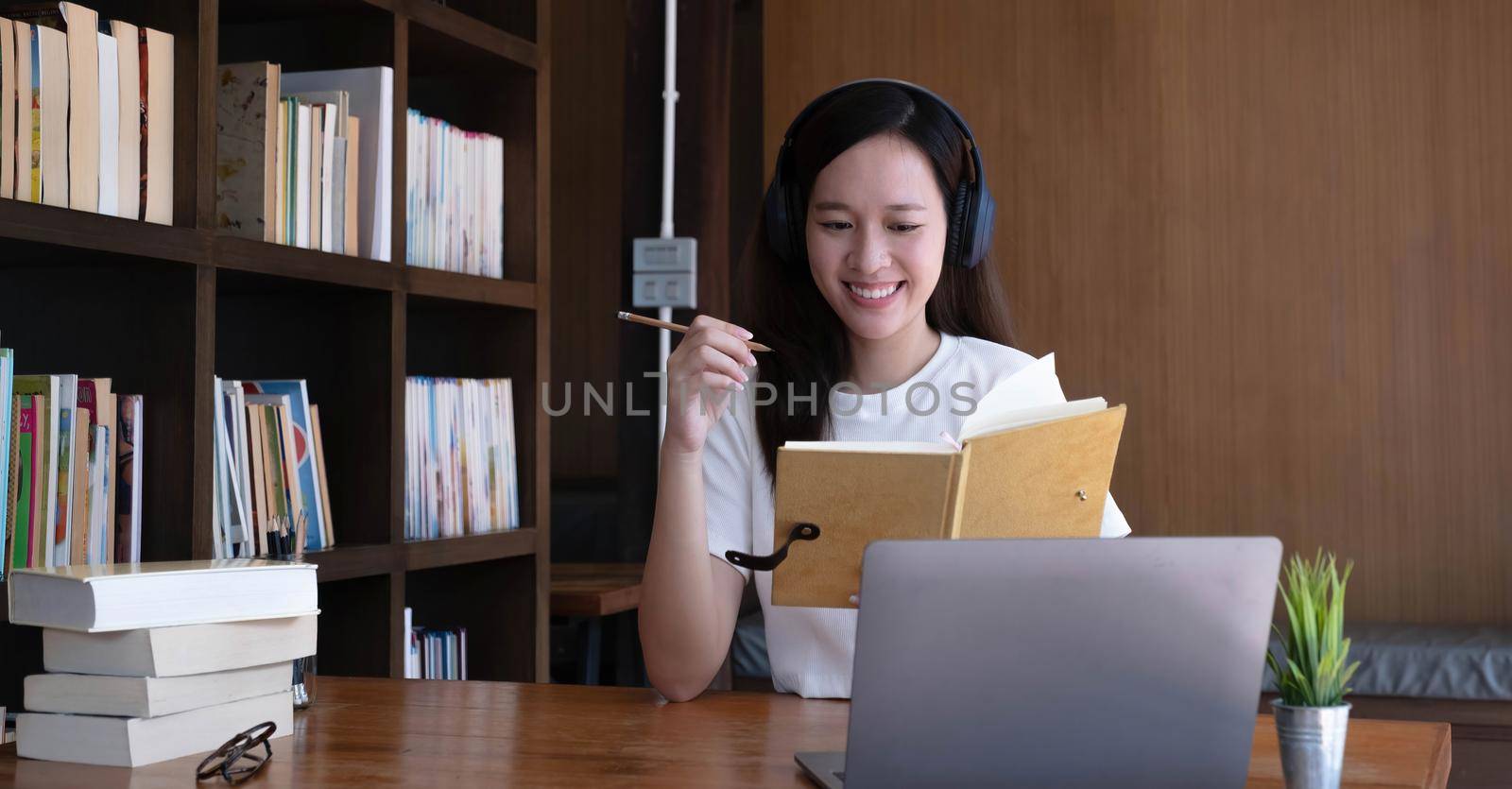 Asian woman wearing headphones study online watching webinar podcast on laptop listening learning education course conference calling, elearning concept..