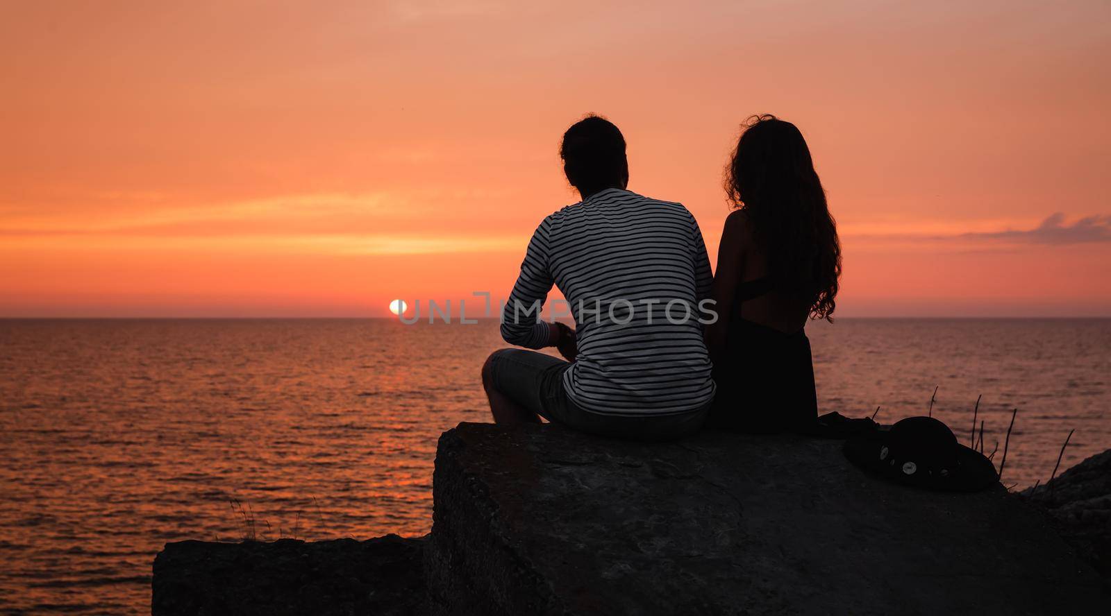 Romantic scene. Silhouette of a young couple in love on the background of sea sunset