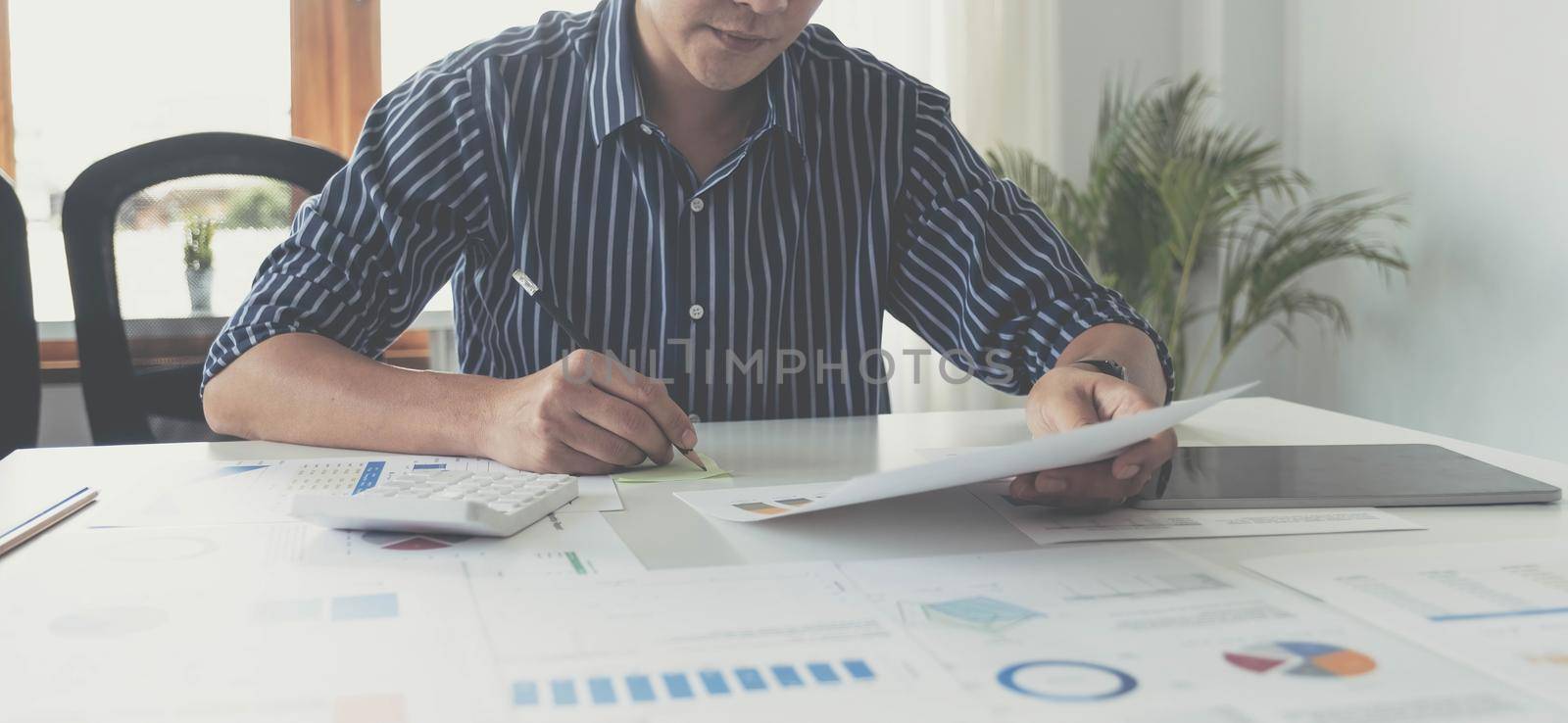 Asian business man hand holding note paper meeting with new startup project use post it notes to share idea discussion and analysis data charts and graphs.Business finances and accounting concept by wichayada