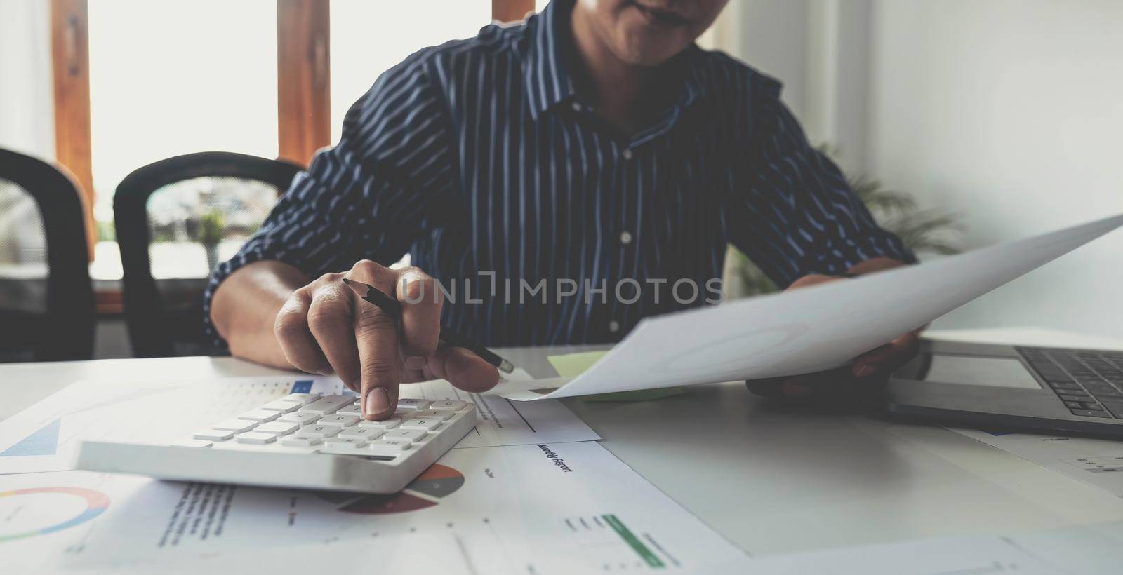 Business man working with new startup project hand pointing graph discussion and analysis data charts and graphs and using a calculator to calculate numbers.Business finances and accounting concept.