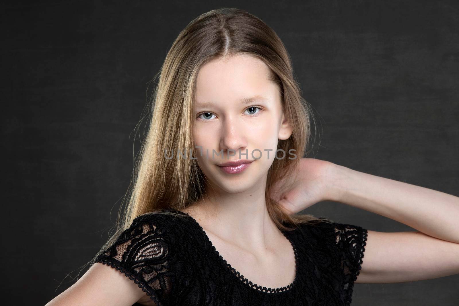 Beautiful teenager girl with long hair on a gray background.